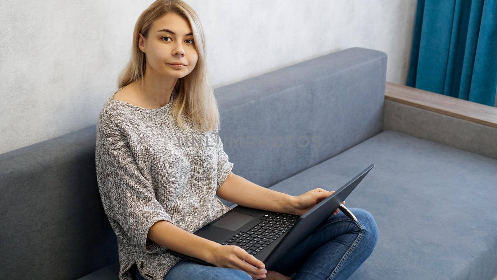 Casual young woman using laptop in living room at home. Working from home in quarantine lockdown