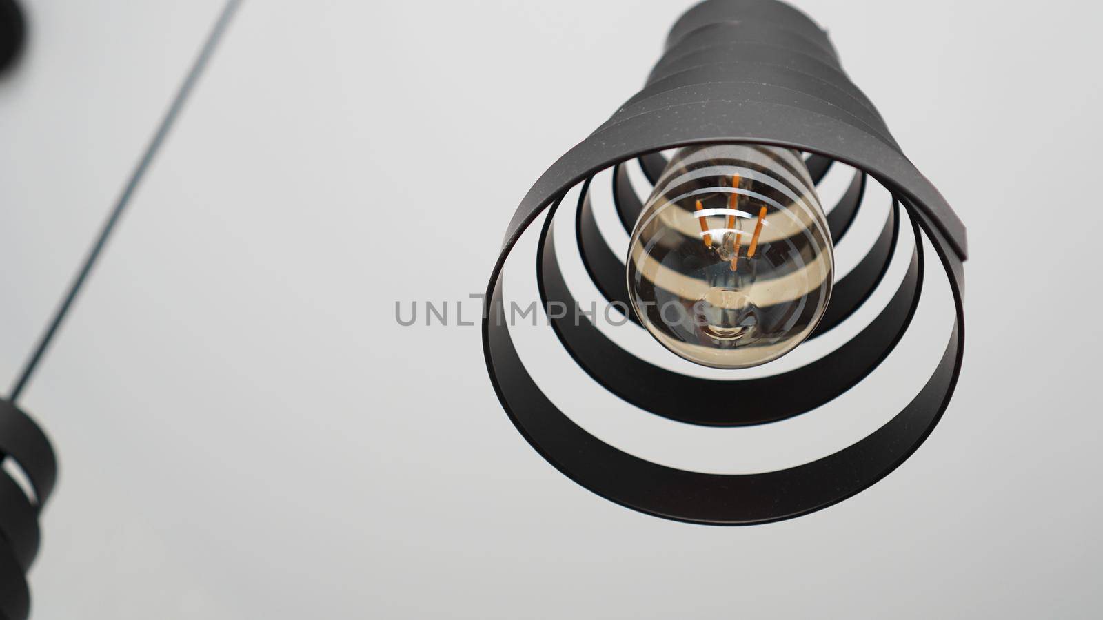 A modern loft chandelier made of black metal spiral in a stylish white interior