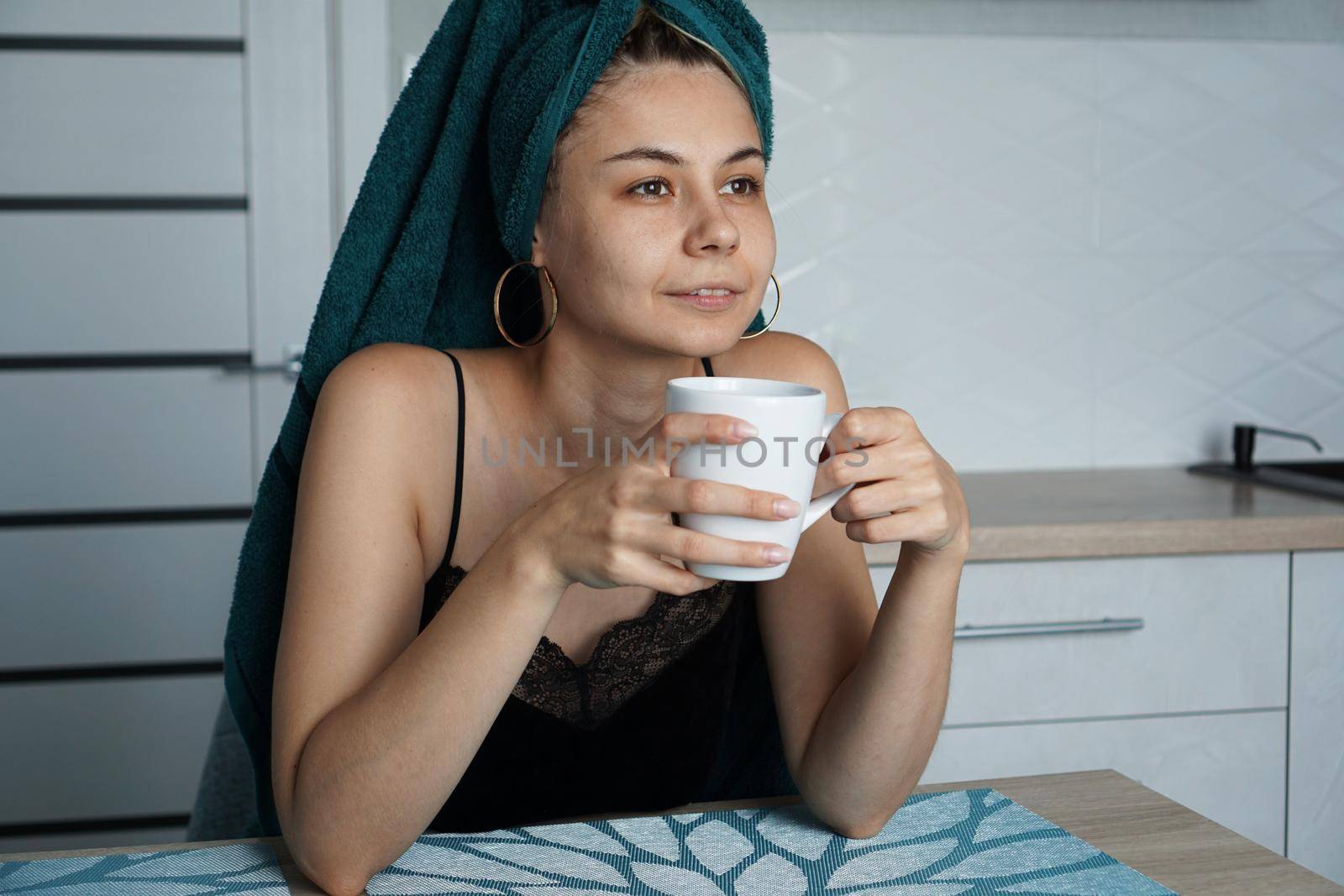 Beautiful woman in a towel on hair with a cup of coffee