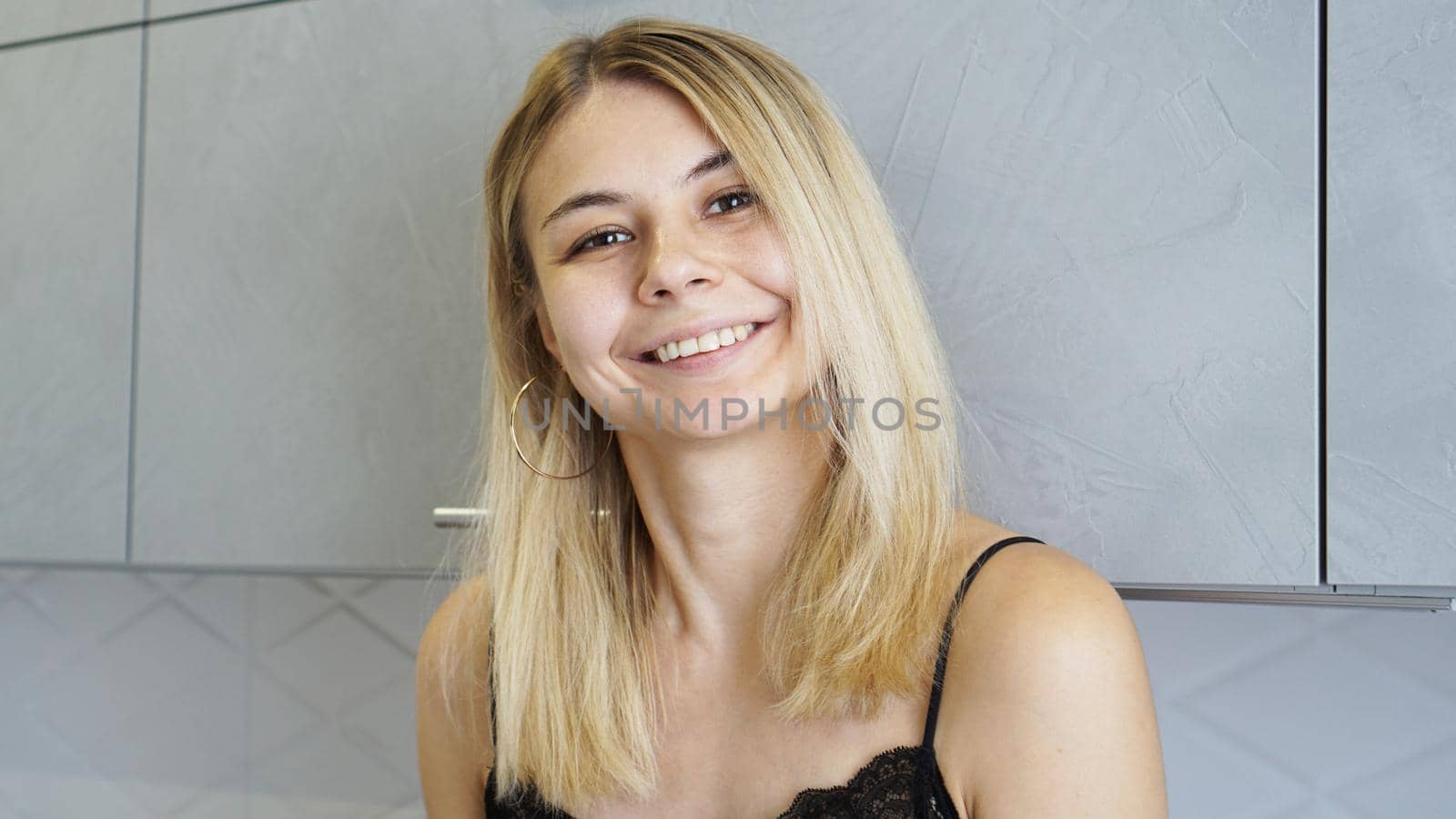 Cheerful young female smiling and looking at camera in cozy styled kitchen