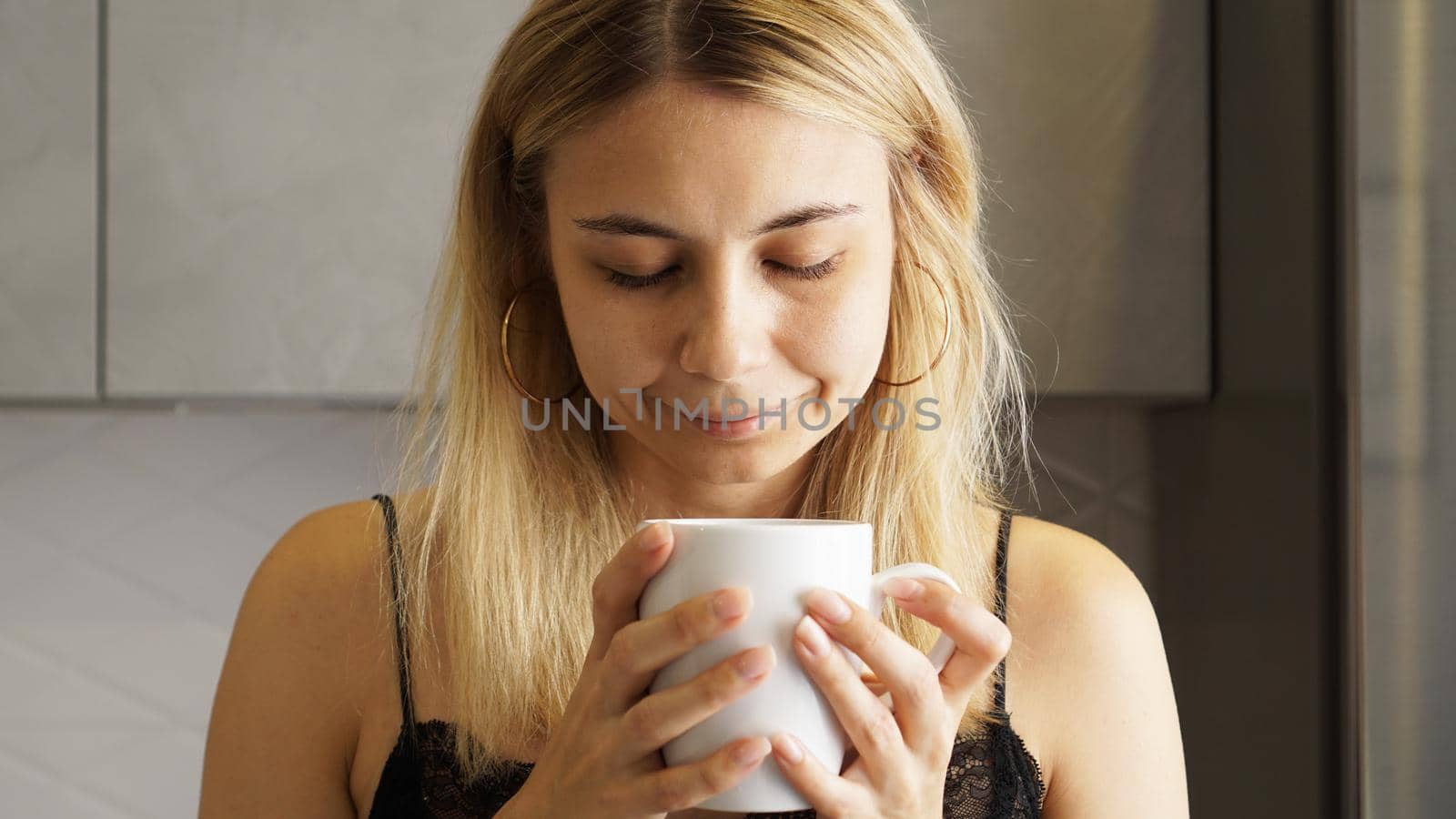 Close up of a woman taking in smell of coffee with her eyes closed in the kitchen