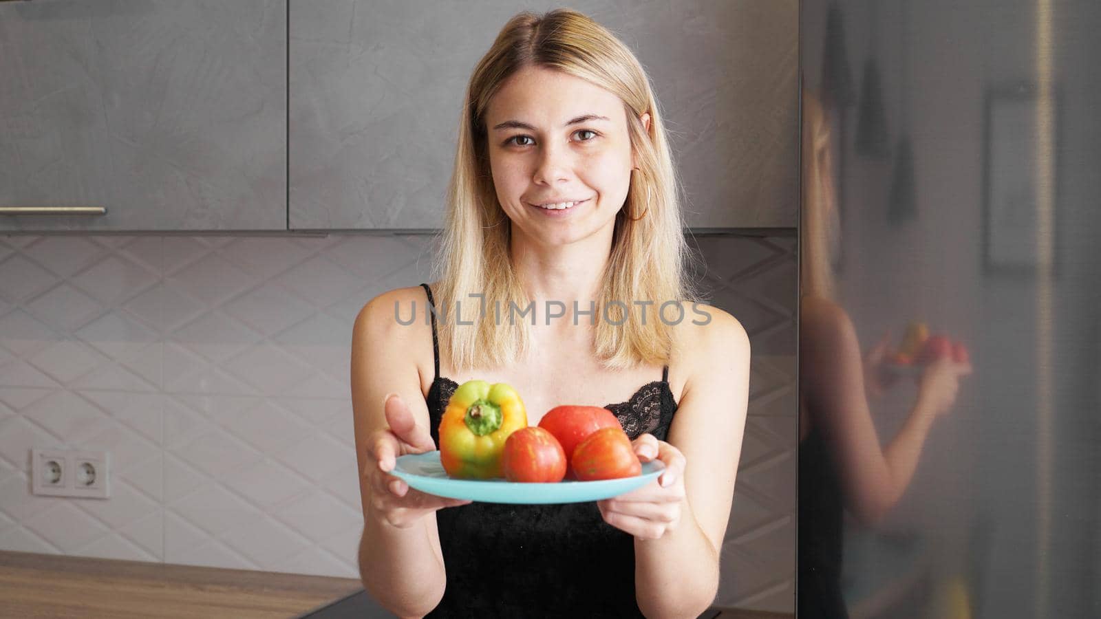 Woman holding plate with fresh vegetables and smiling by natali_brill