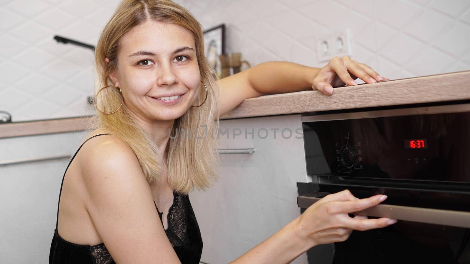 Young woman cooking in the kitchen opening the oven door