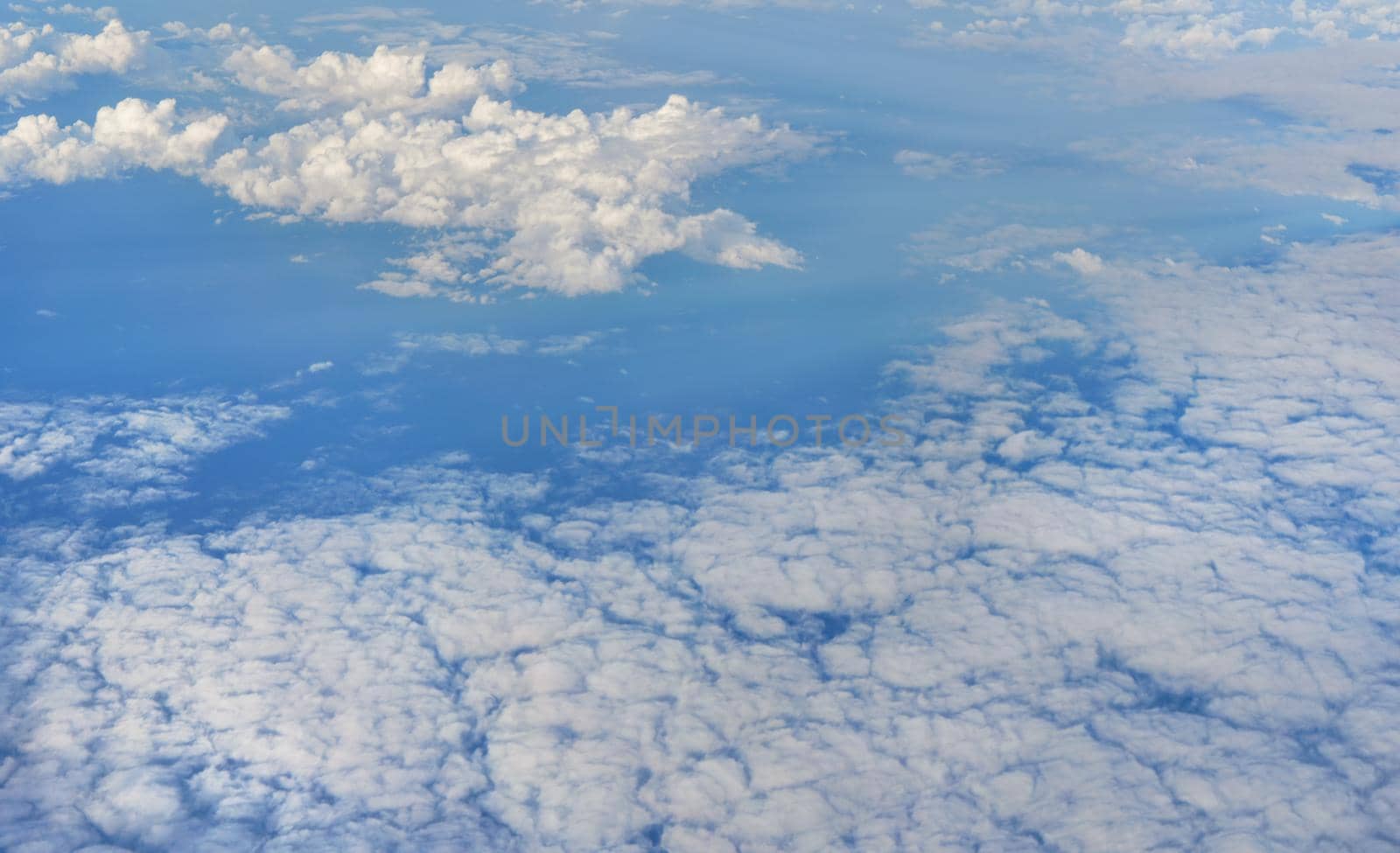 Fluffy sky clouds lit by afternoon sun, as seen from commercial airplane flying over by Ivanko