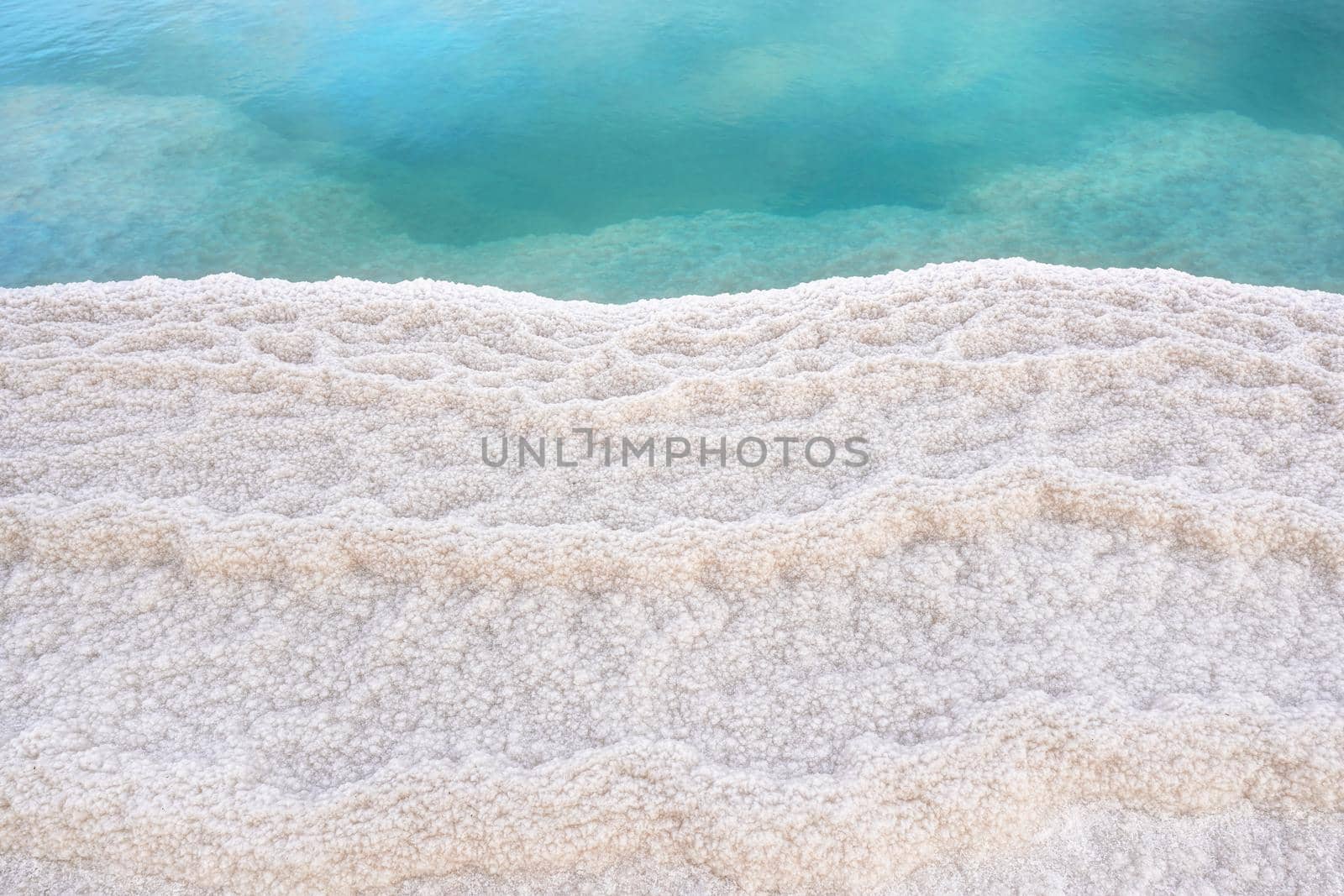 Shore of Dead sea in Ein Bokek, Israel, white salt crystals outside and at the bottom, turquoise clear water by Ivanko