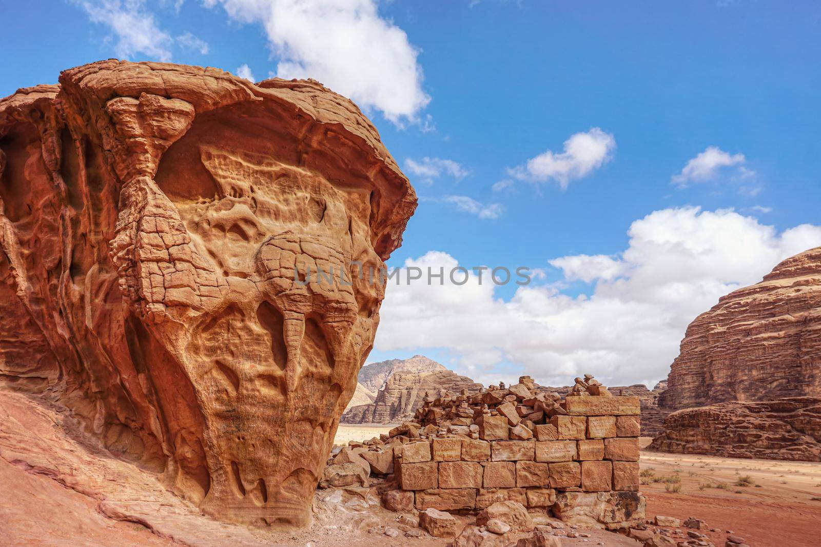 Stone bricks wall remains with rocky cliffs near on Wadi Rum desert near Lawrence's Spring tourist spot.