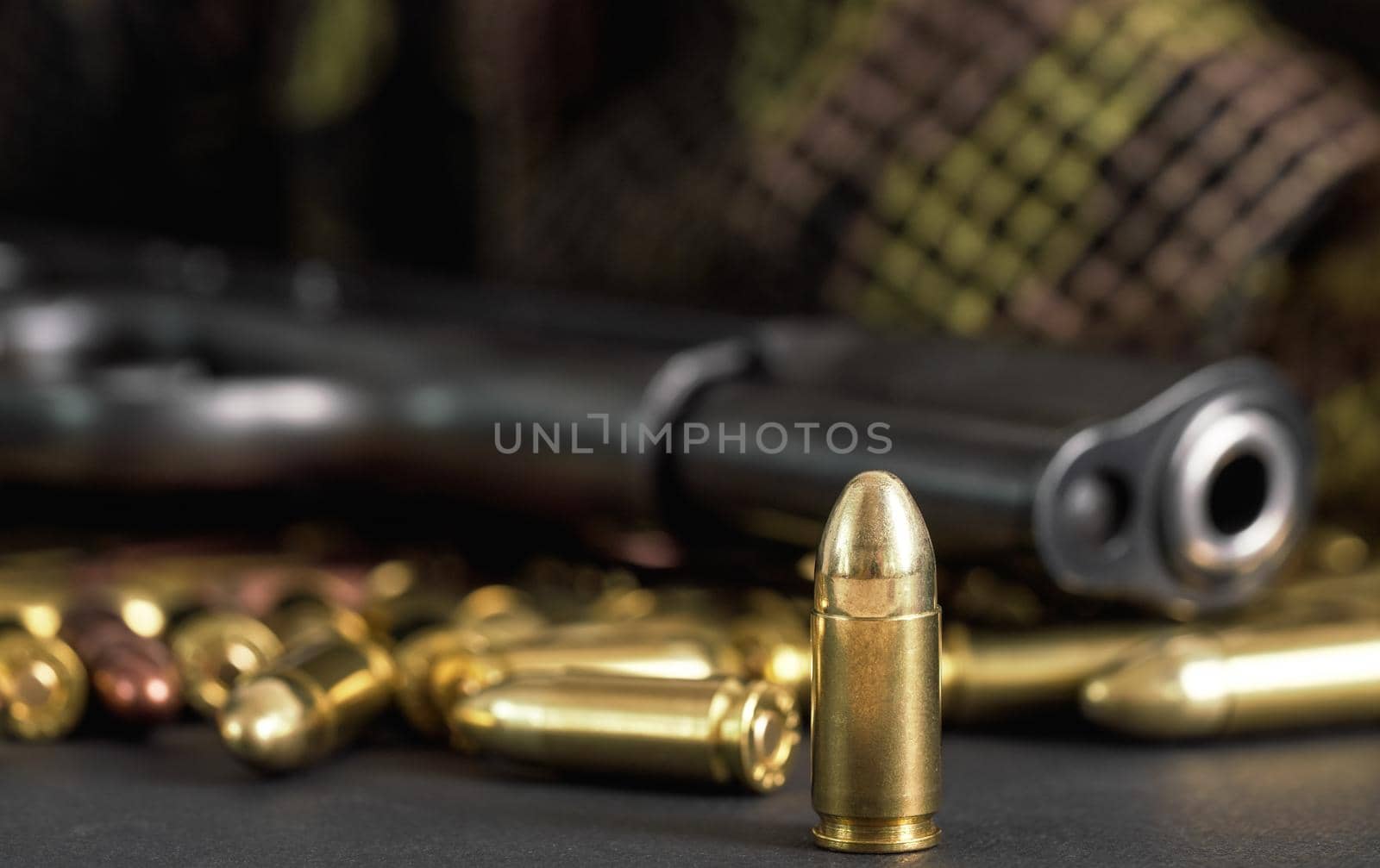 Single yellow brass bullet detail, black metal gun in background.