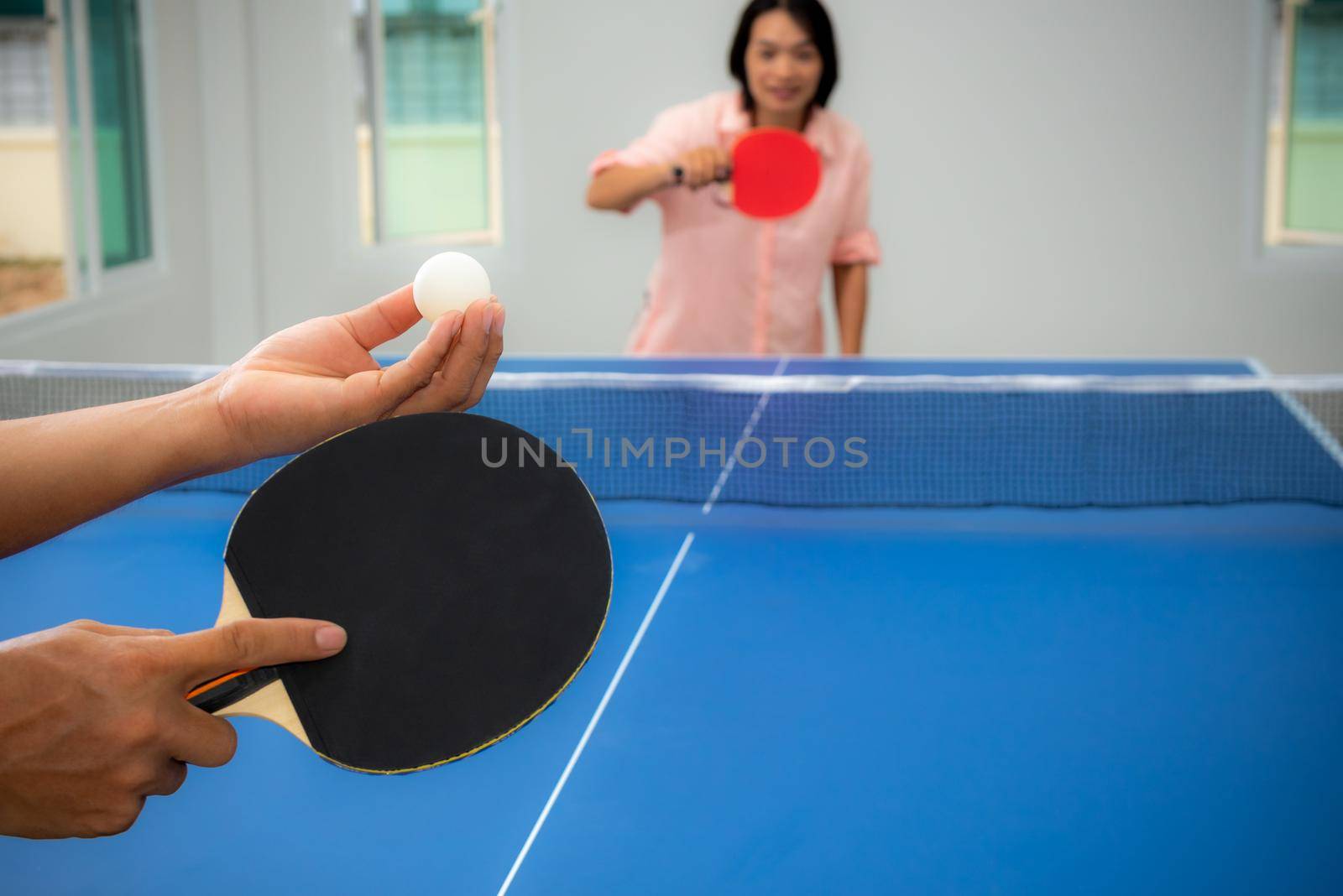 Adult Asian woman are waiting to start playing table tennis or Ping pong indoor. Leisure with competing in sports games in the house, Recreation or exercise stay at home with the family in Thailand