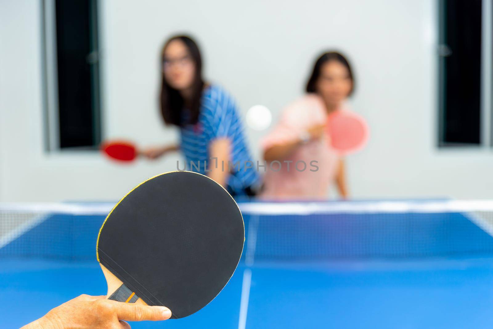 Asian family fun playing table tennis or Ping pong indoor together leisure with competing in sports games at house. Blur mother and daughter enjoy recreation or exercise stay at home for background