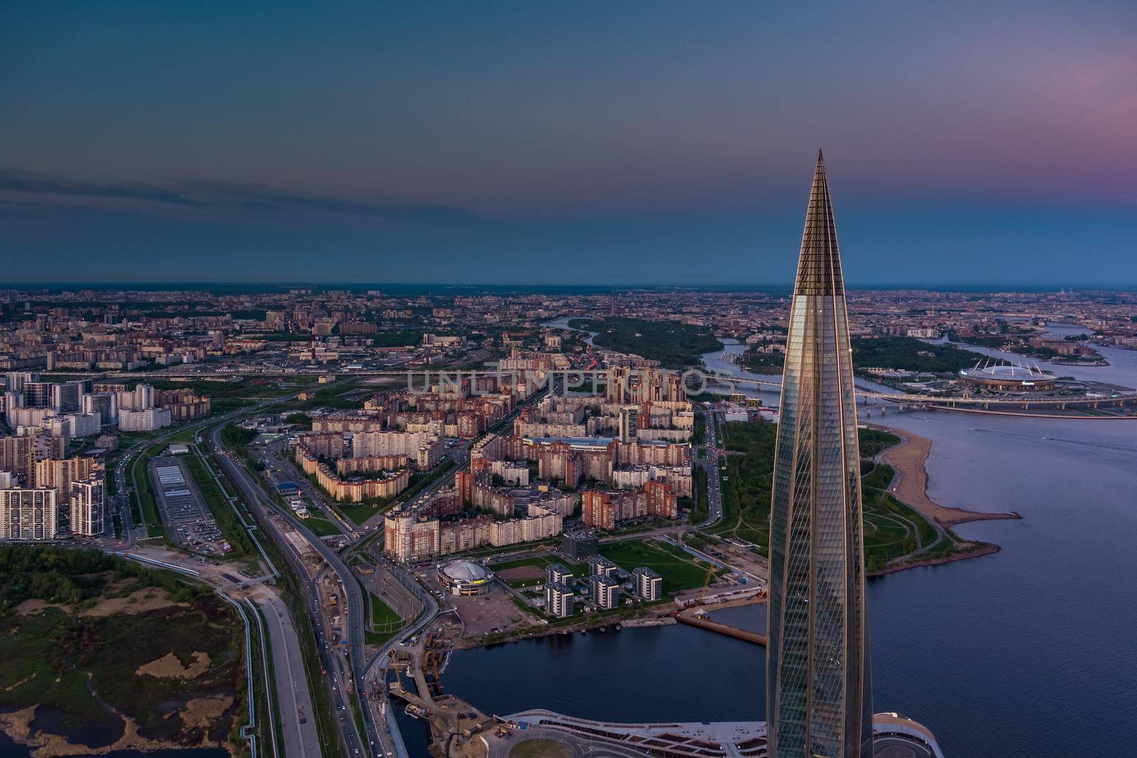 Russia, St.Petersburg, 16 May 2021: Drone point of view of highest skyscraper in Europe Lakhta Center at pink sunset, Headquarters of the oil company Gazprom, stadium Gazprom Arena on background. High quality photo