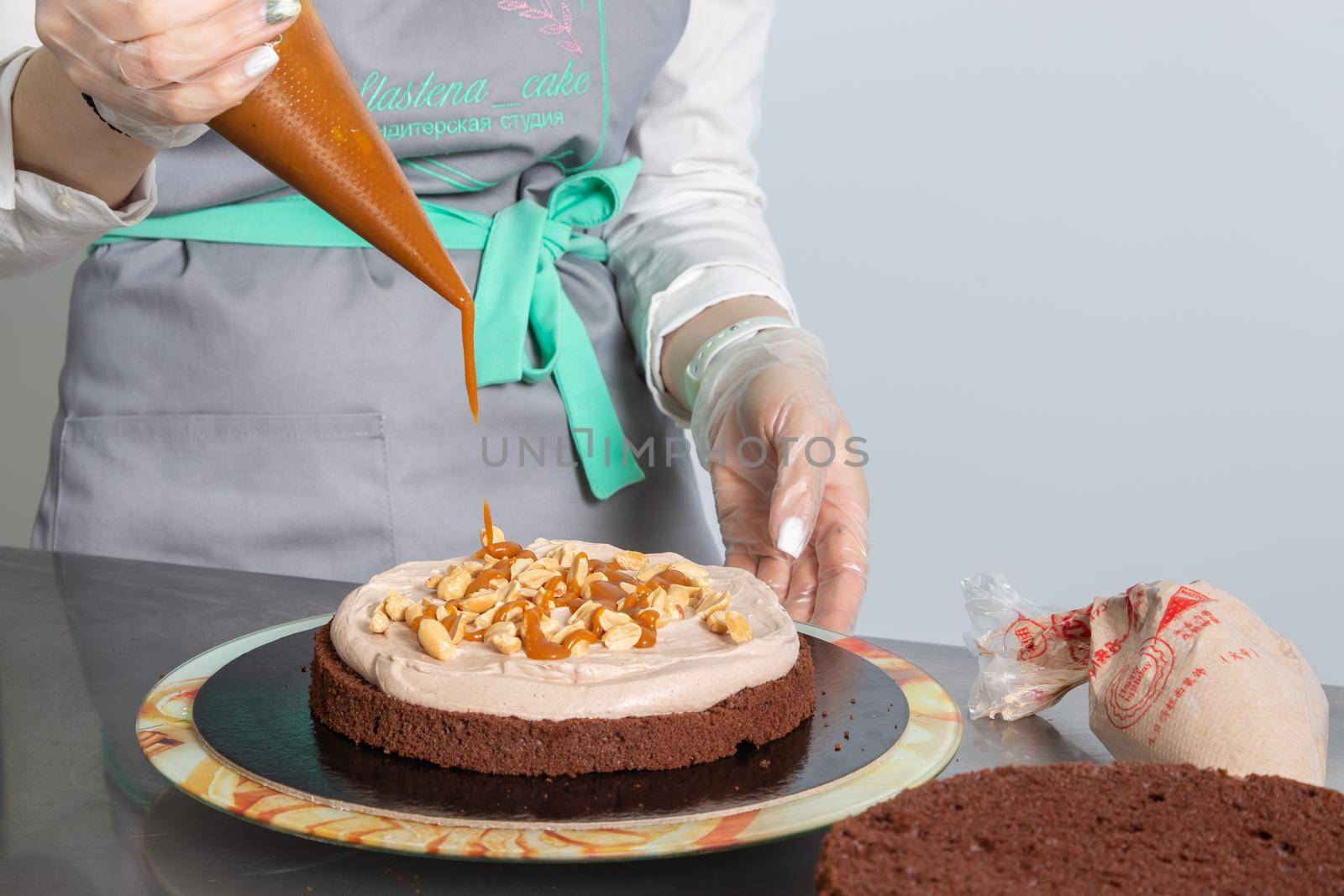 Moscow, Russia - April 18, 2021: Confectioner collects biscuit chocolate cake and decorates layers.
