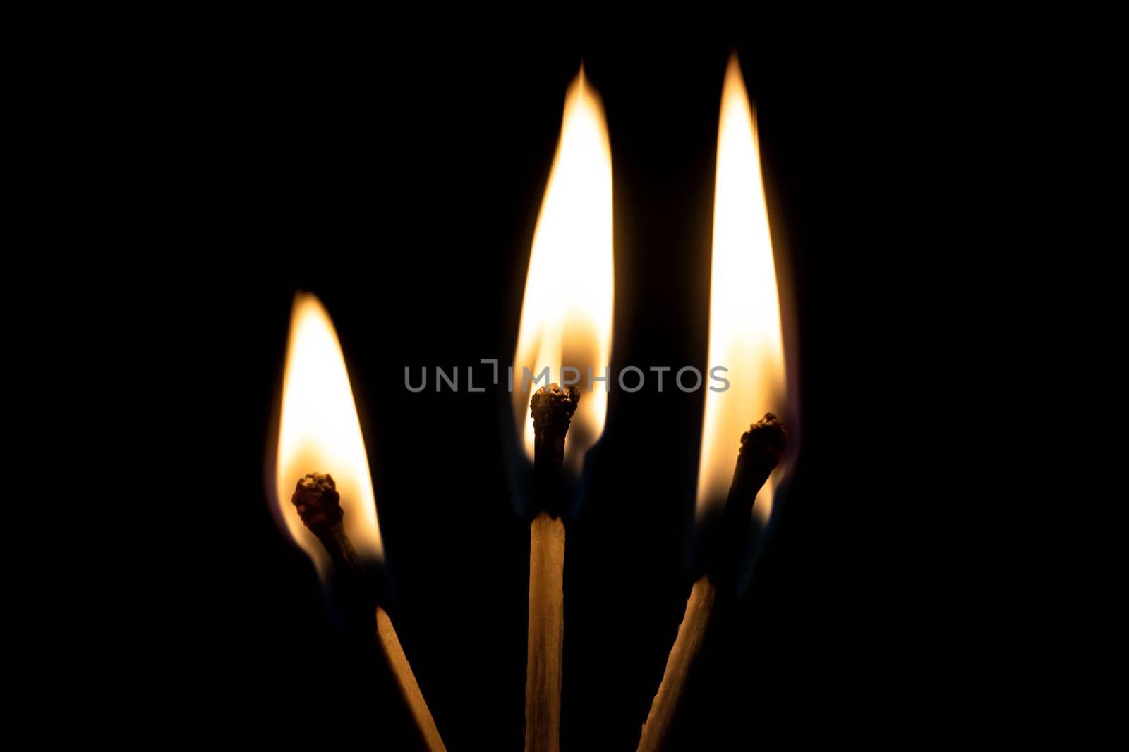 Three burning matches in the dark close up, isolated on black