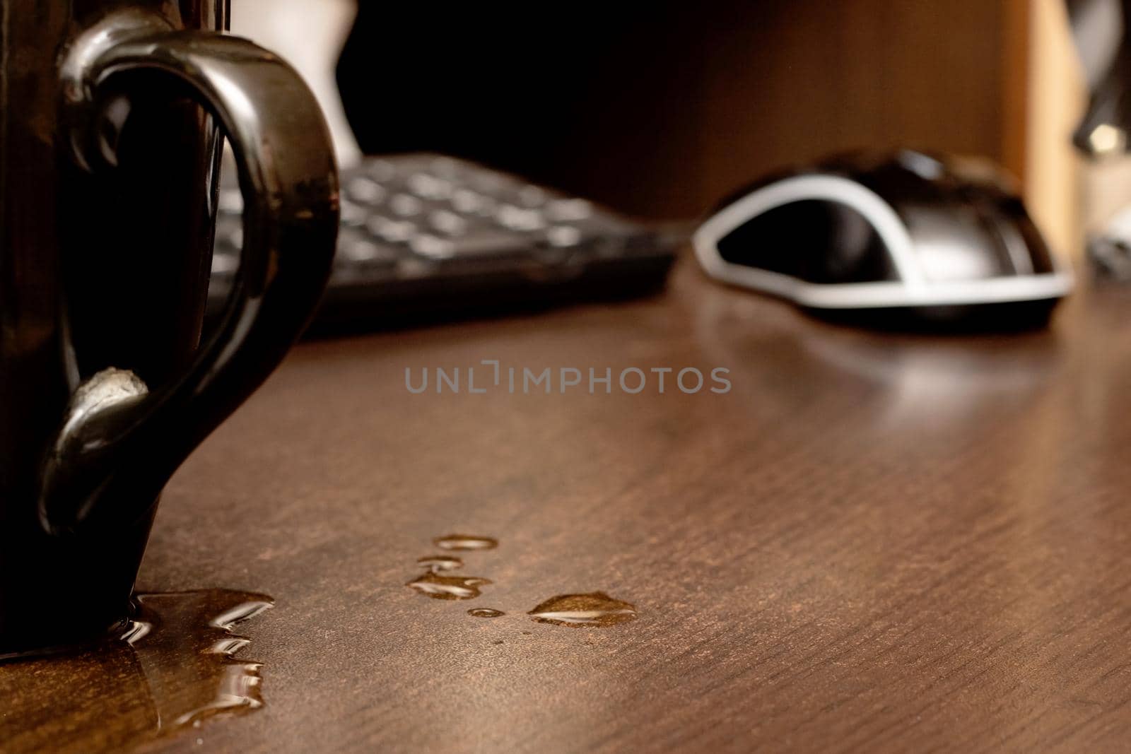 Spilled drink from the cup on the background of the computer