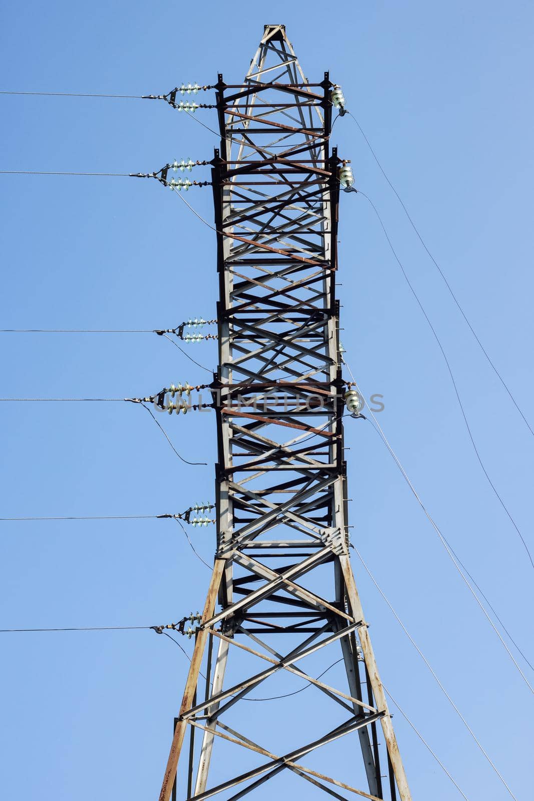 Metal pole with electrical networks on a blue sky background close up