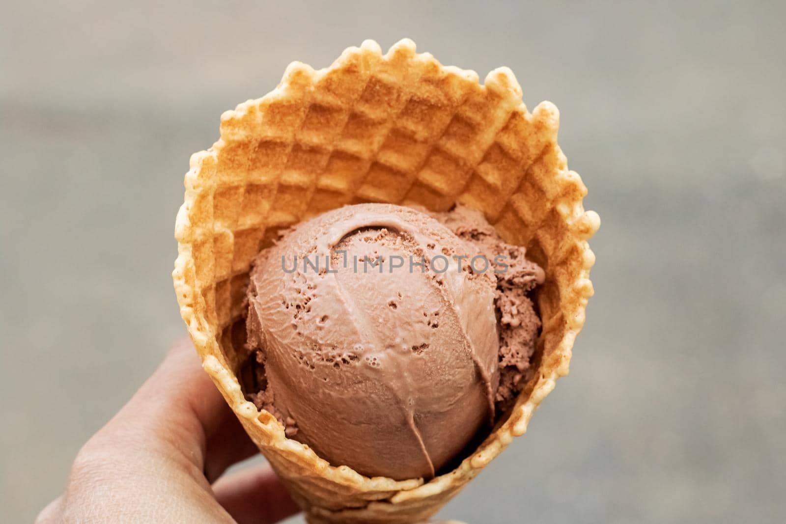 Chocolate ice cream in a waffle cone on gray background