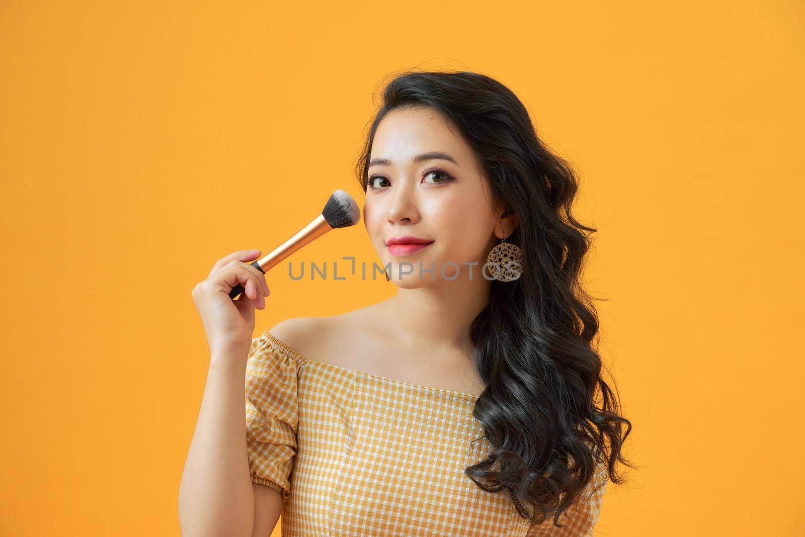 Portrait of attractive young Asian woman with beautiful skin holding brush for make up.