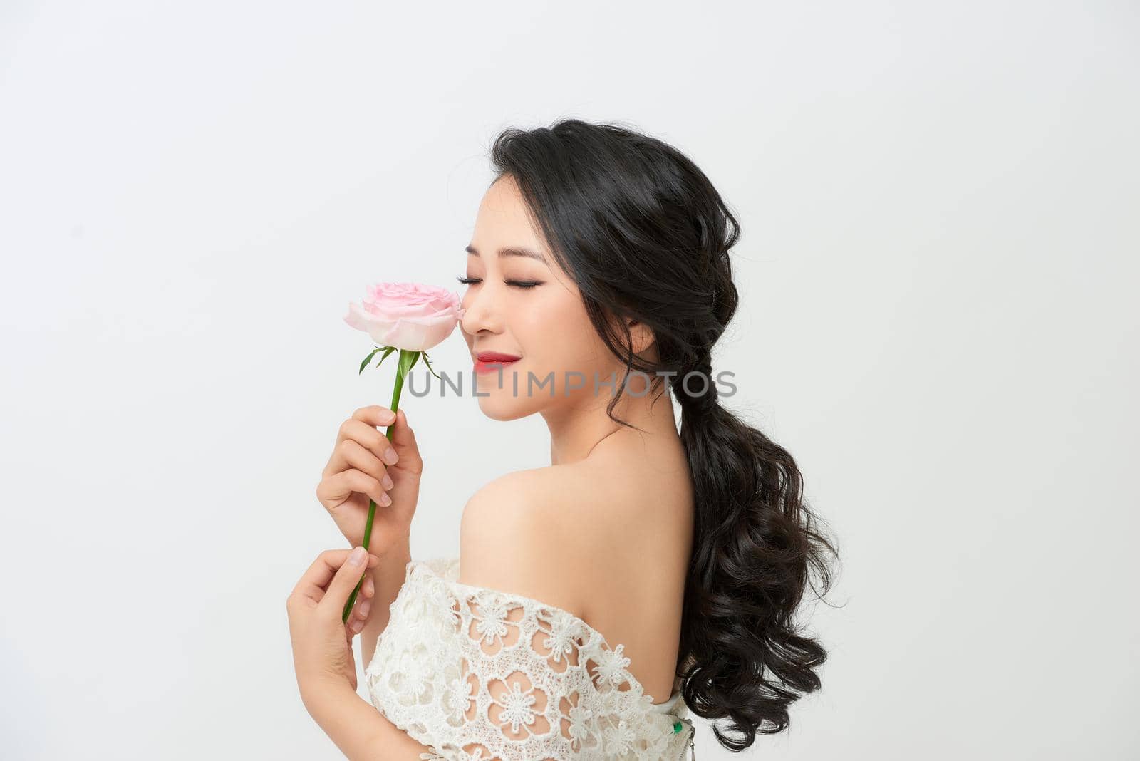 Gorgeous young bride with a rose bouquet isolated against white background.