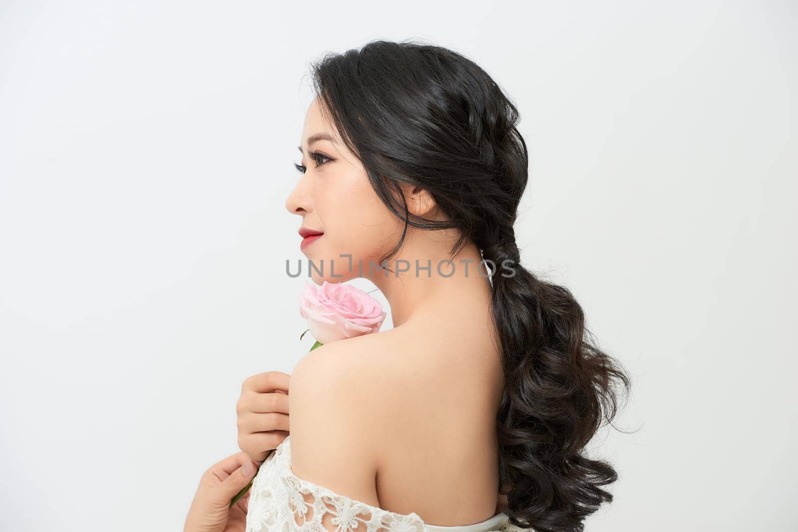 Close-up portrait of young beautiful bride with stylish make-up and hairdo holding bouquet