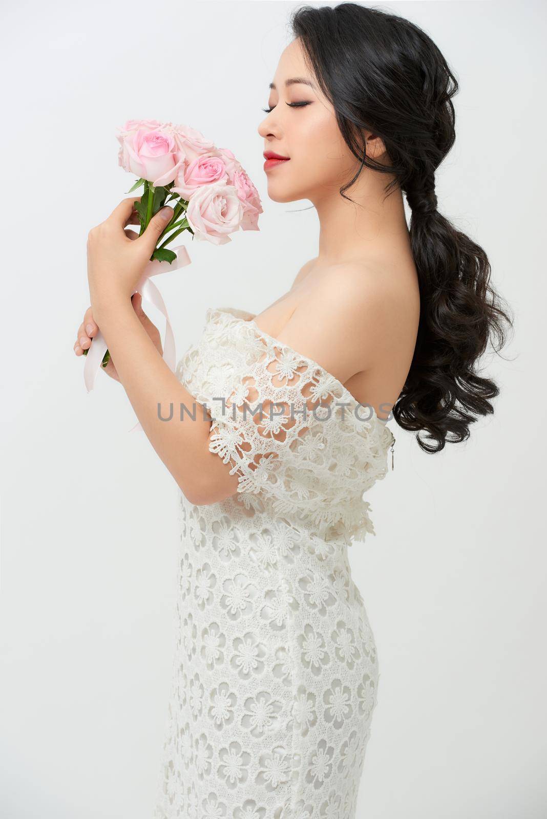 Young beautiful woman in a white dress posing with a bouquet of roses