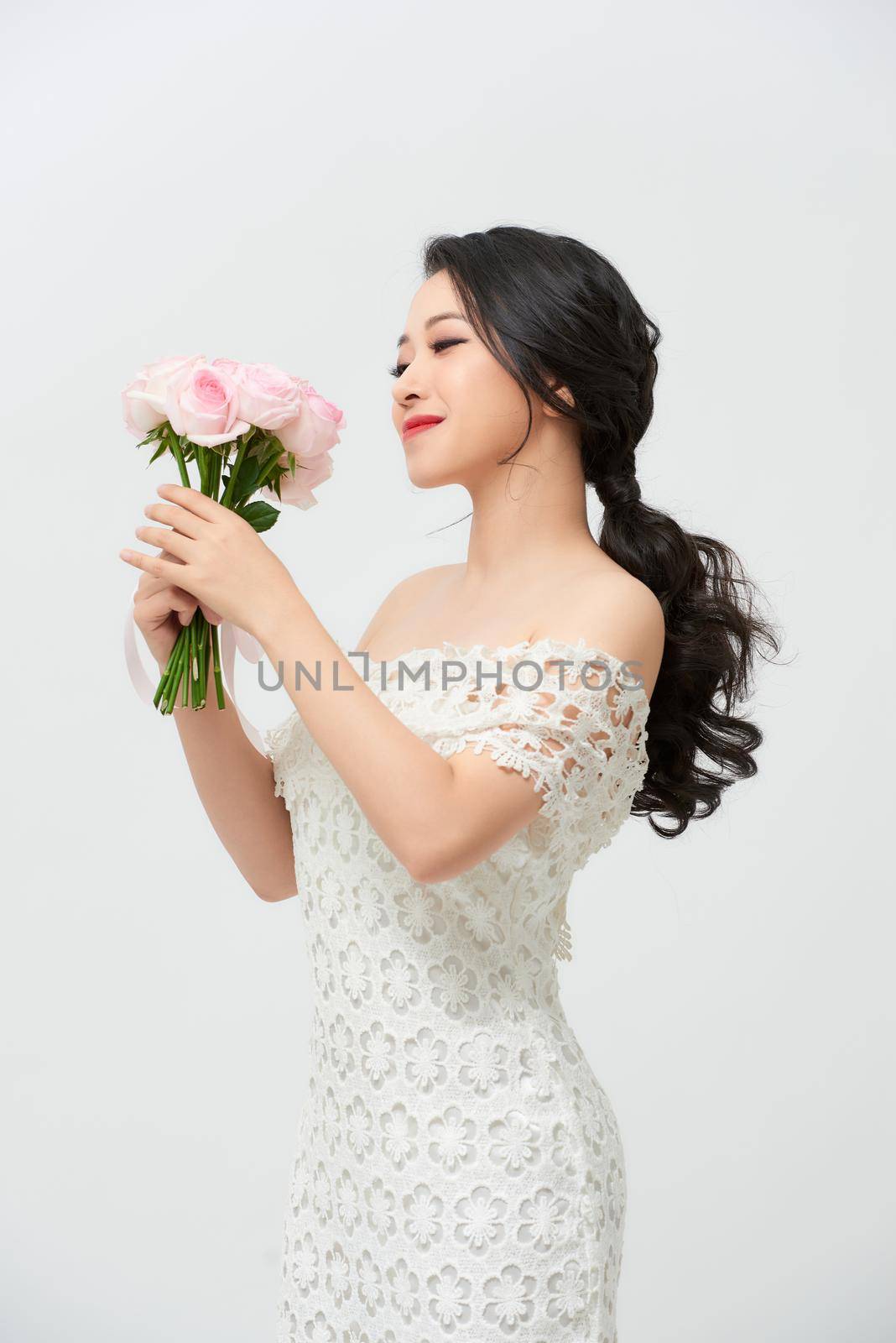 Young attractive Asian model like a bride with bridal bouquet at studio looking by makidotvn