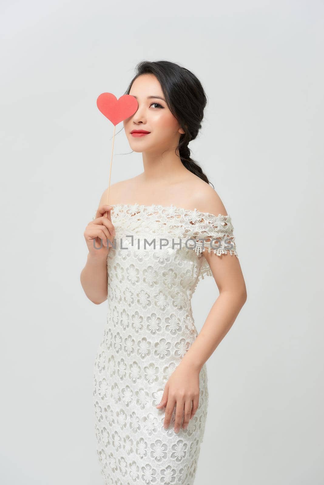 Studio portraits with beautiful bride isolated on white background. She is holding red heart. by makidotvn