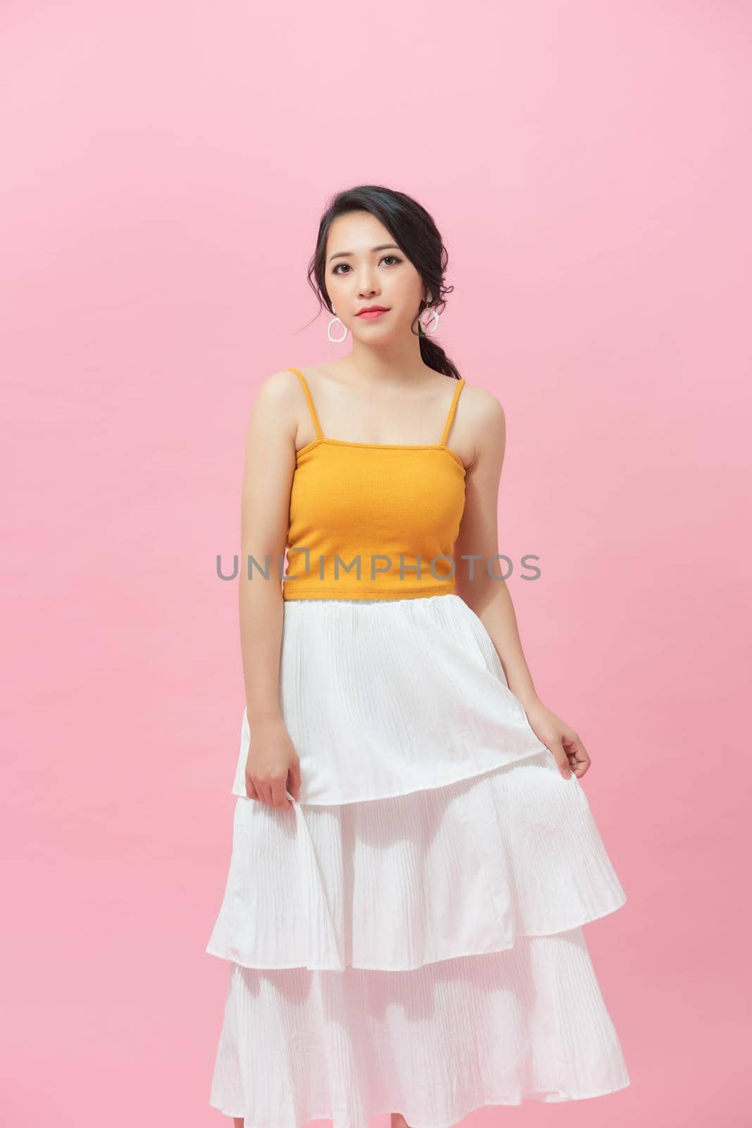 Happy beautiful woman in yellow, white dress posing in studio isolated on white background.