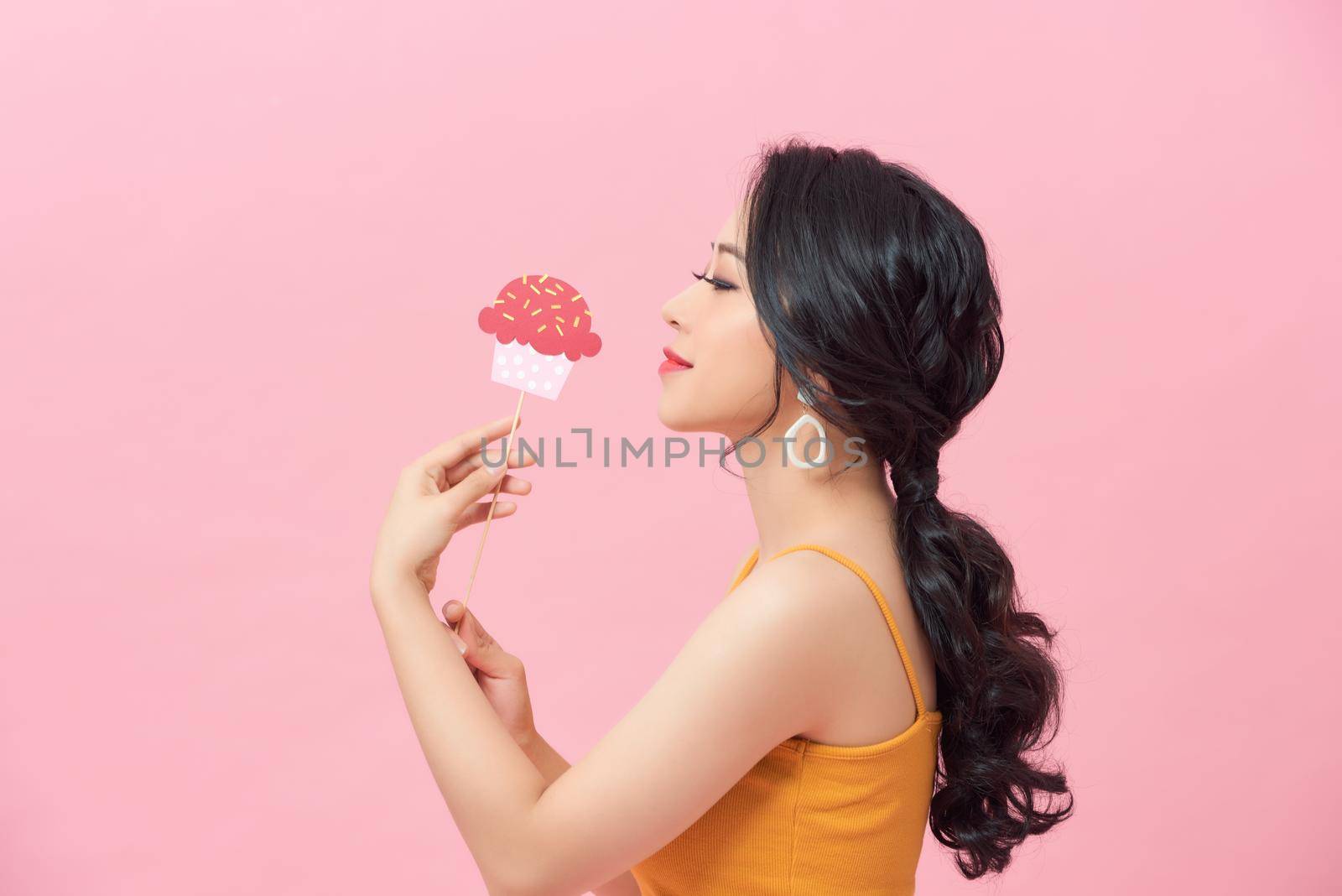 Charming lady hold cupcake shape on stick good mood nice day over pastel pink background
