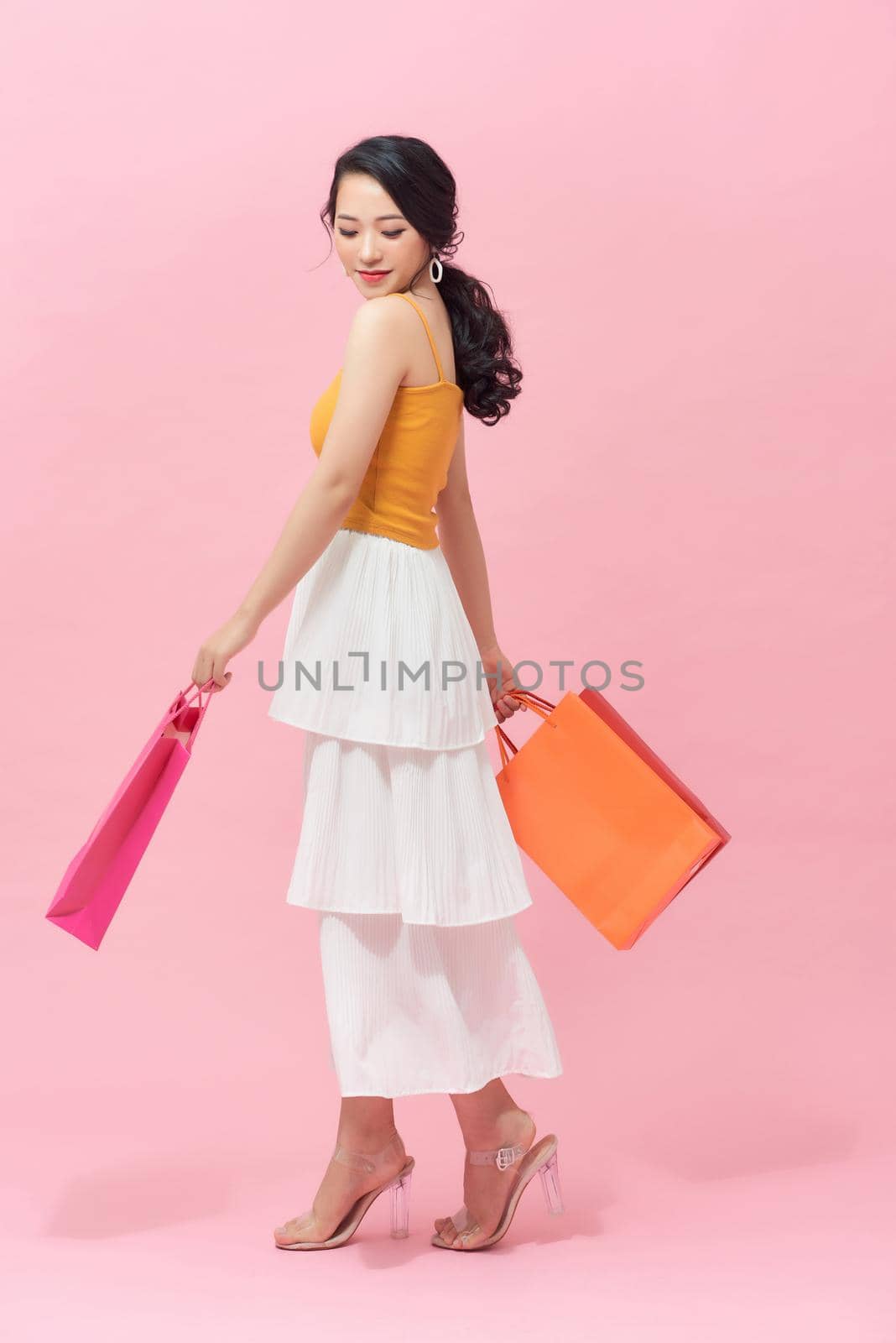 chic and stylish woman walking ahead - holding some shopping bags