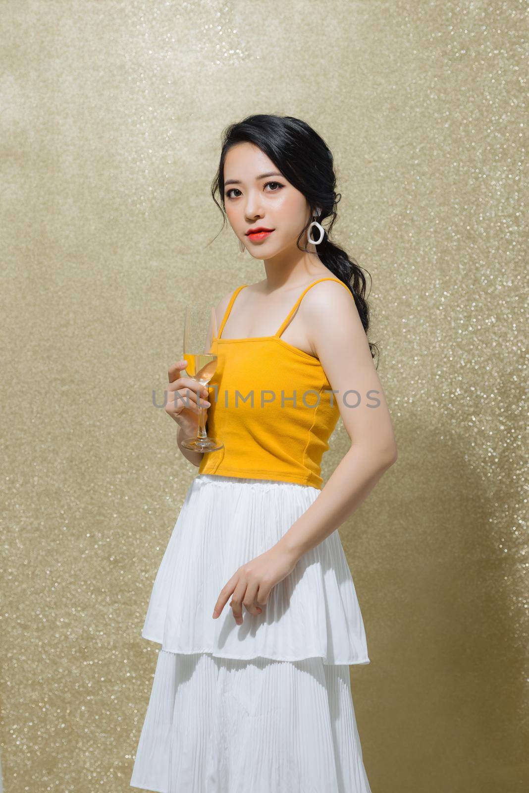 Young attractive young woman holding champagne wine over gold background. Party, holiday, Christmas, New Year concept by makidotvn