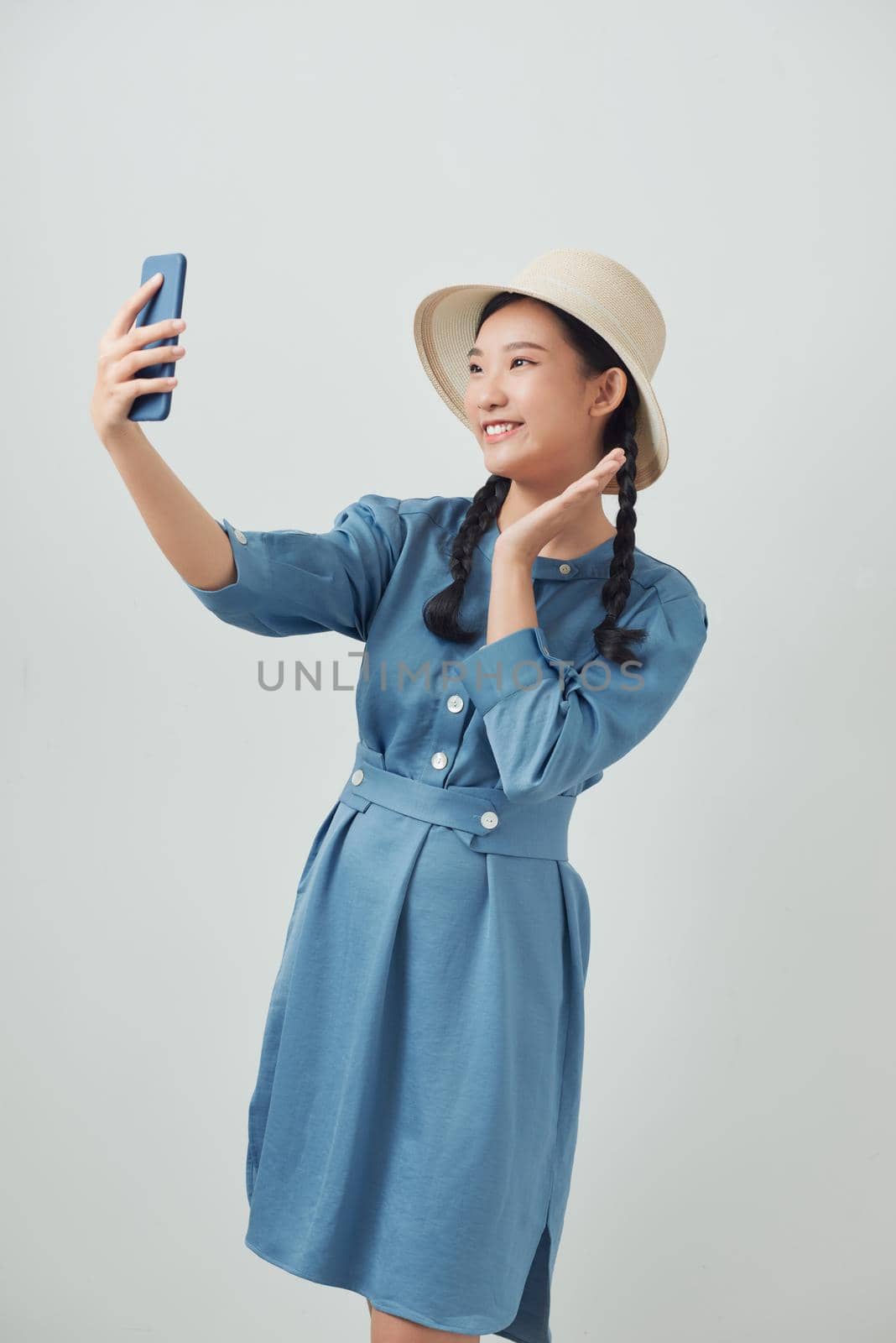 Emotional young woman taking selfie on white background