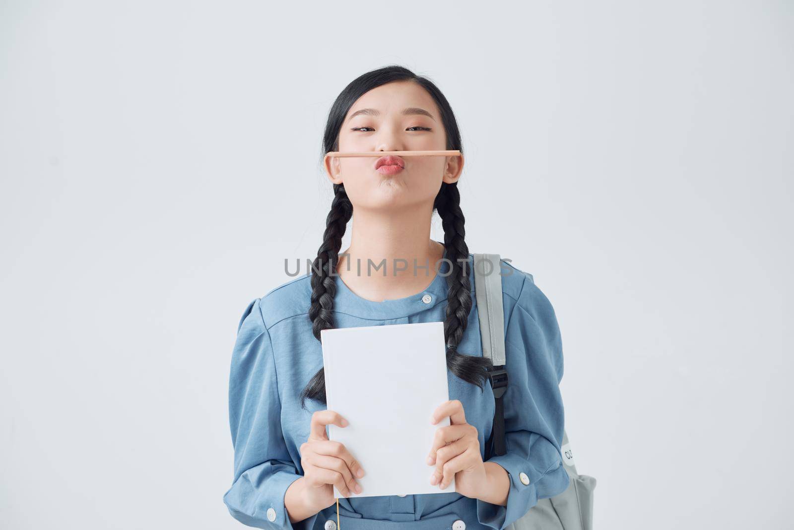 Funny asian woman with notebooks holding pencil with lips, positive lifestyle by makidotvn