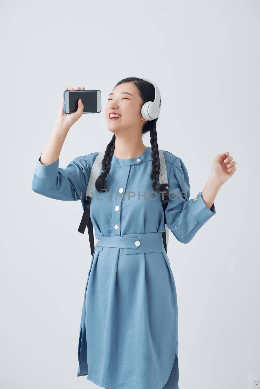 Asian women are listening to music and she sings in the room happily.