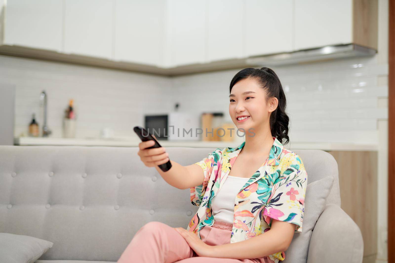 Jolly blond woman watching TV lying on a sofa at home