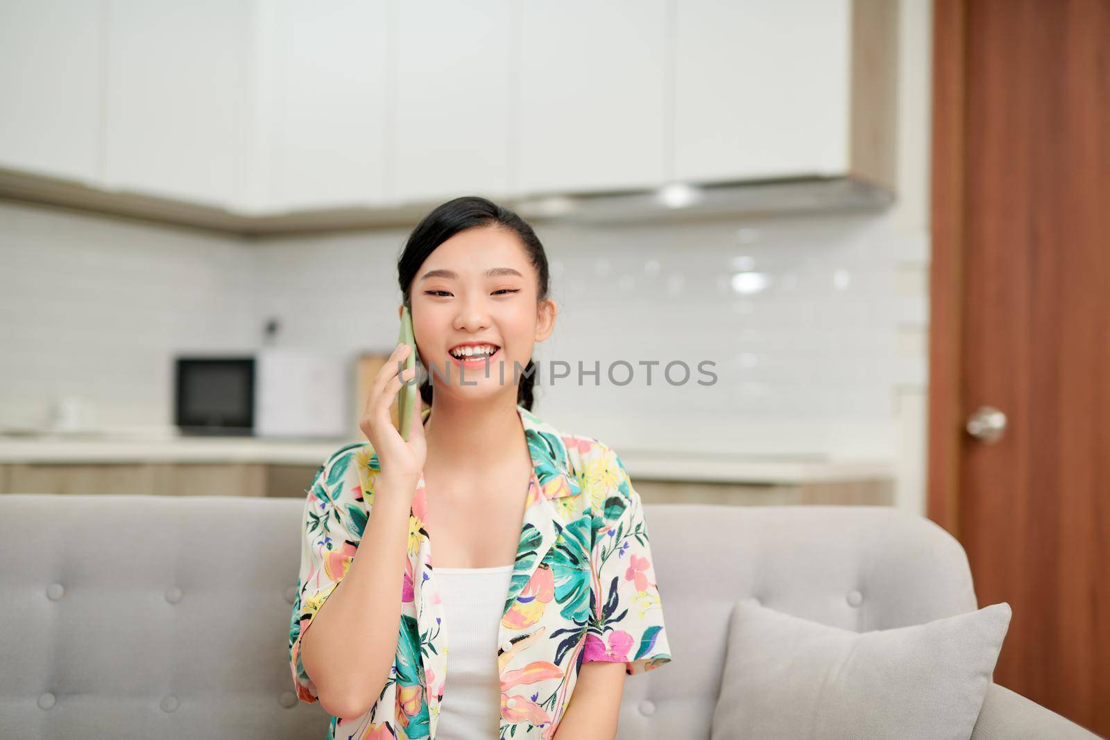 Young woman in casual talking on mobile at home on the sofa. 