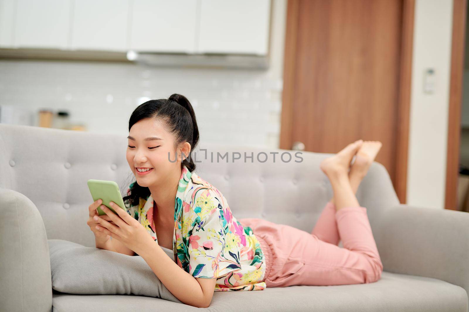 Happy millennial hispanic teen girl checking social media holding smartphone at home. 