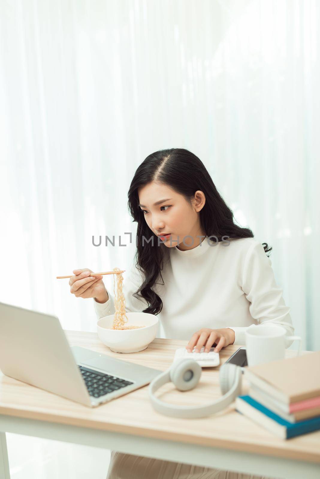 Portrait of young Asian woman freelancer working with laptop at her home and eating Asian food with takeaway.  by makidotvn