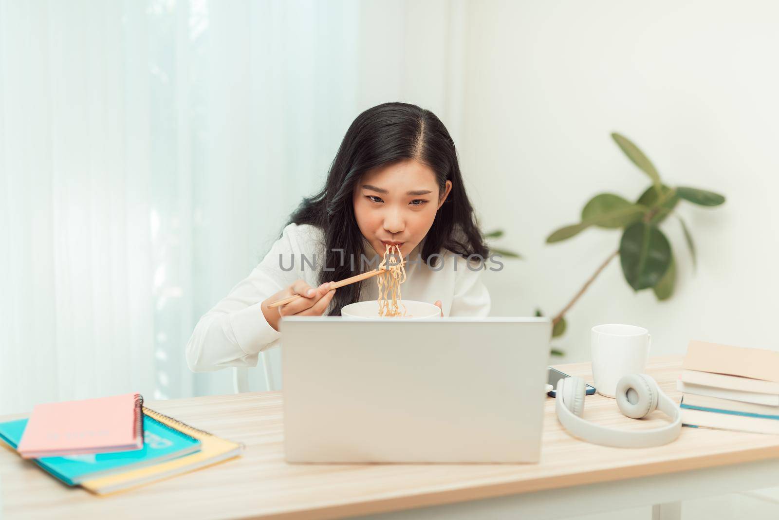 Asian business woman eating noodle at office desk for lunch time by makidotvn