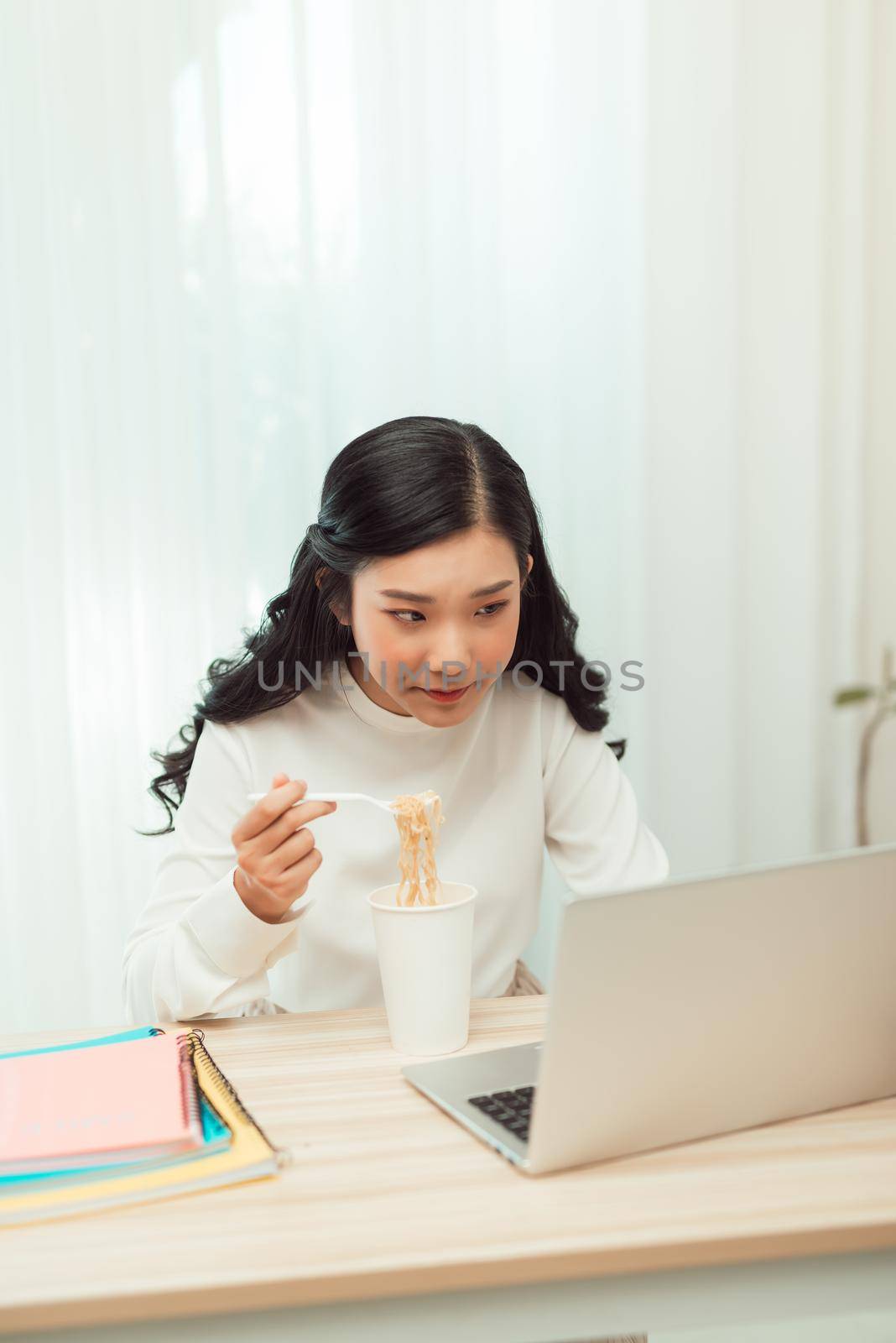 Portrait of young Asian woman freelancer working with laptop at her home and eating Asian food with takeaway.  by makidotvn