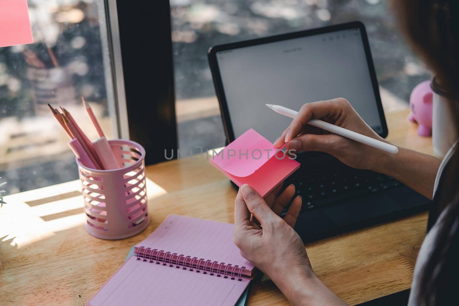 Close up businesswoman taking note on postit. Female working with digital tablet at cafe.