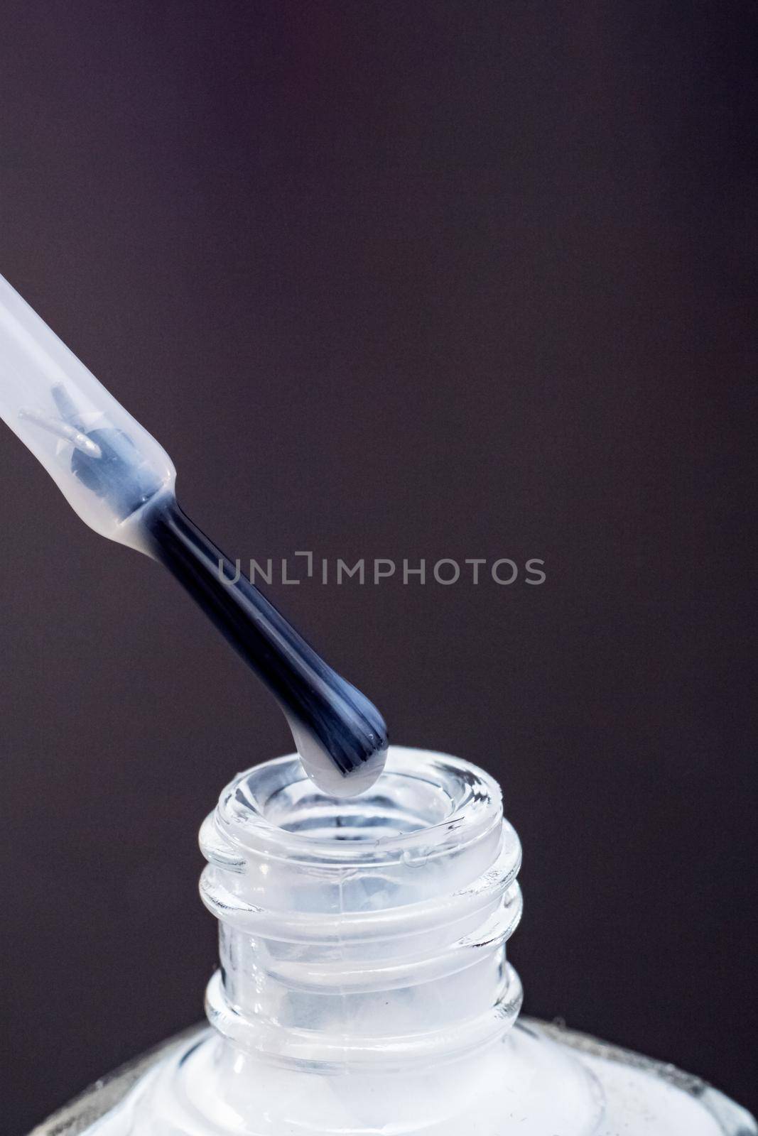 White nail polish and brush for applying manicure on a purple background