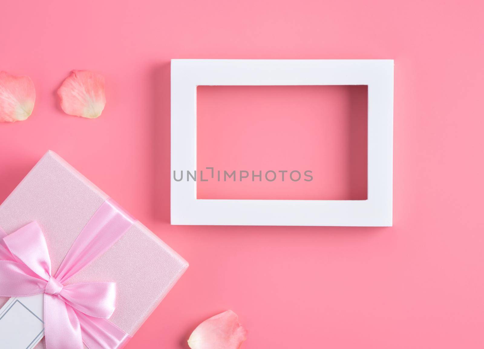 Valentine's Day design concept background with pink petals and gift box on pink background