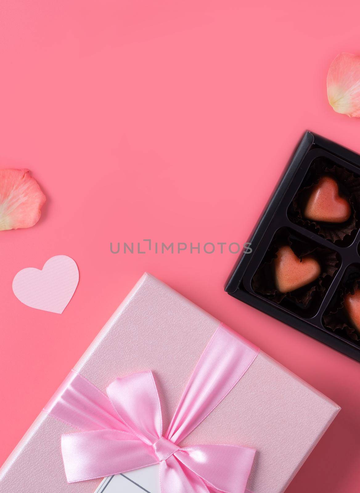 Valentine's Day design concept background with pink petals and gift box on pink background