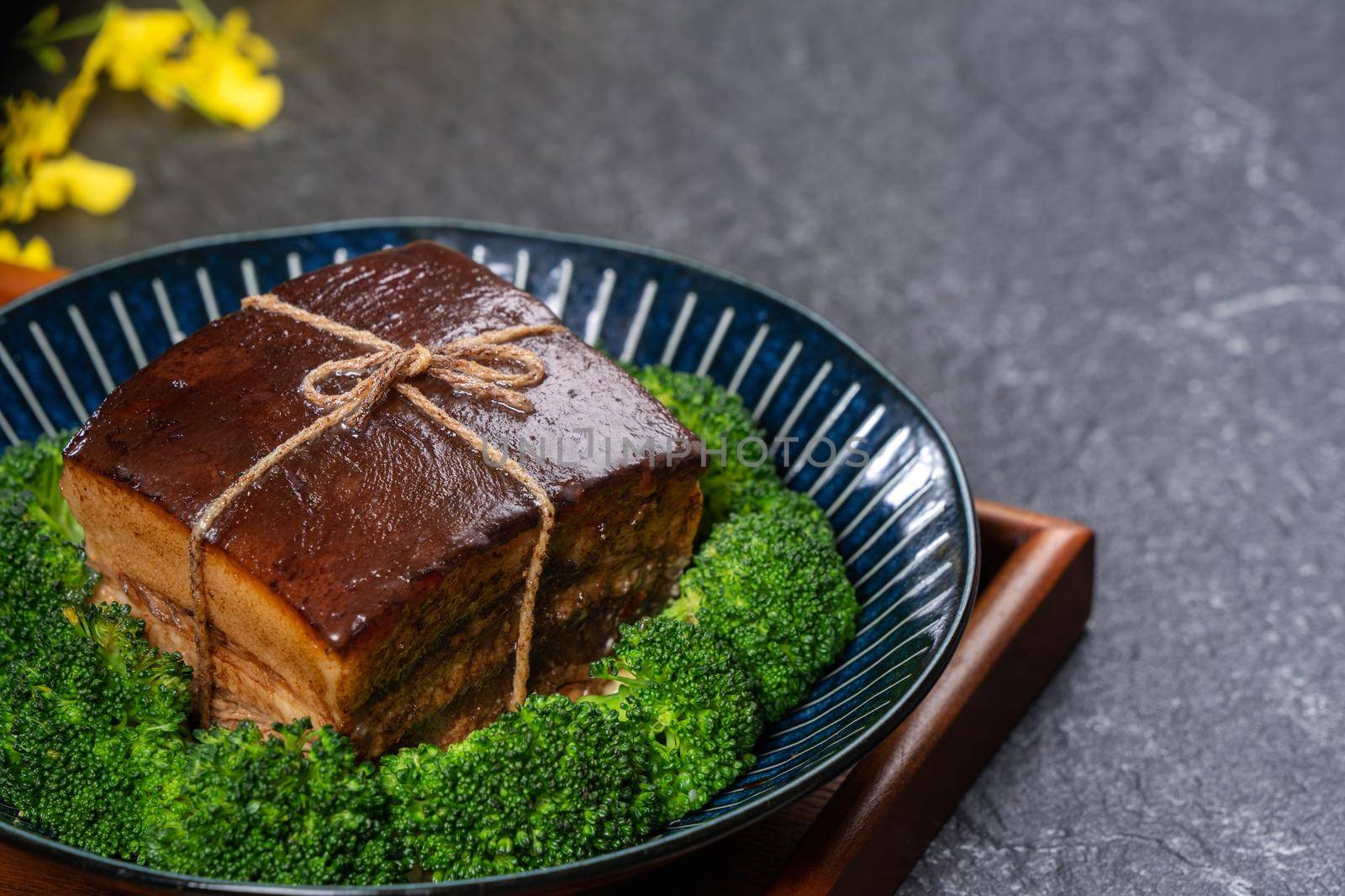 Dong Po Rou (Dongpo pork meat) in a beautiful blue plate with green broccoli vegetable, traditional festive food for Chinese new year cuisine meal, close up.