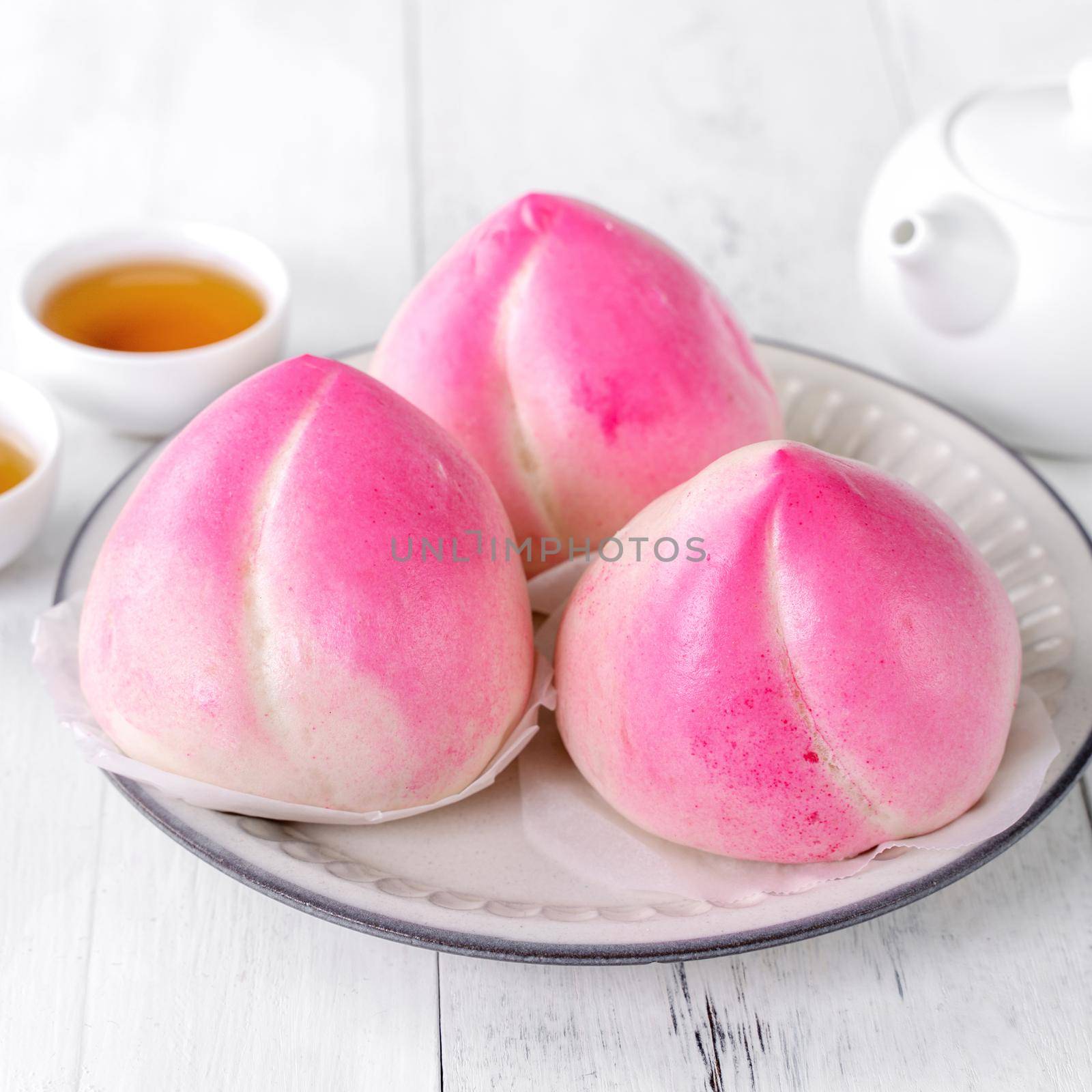 Pink Chinese peach birthday bun food named Longevity peach shoutao on white table background.