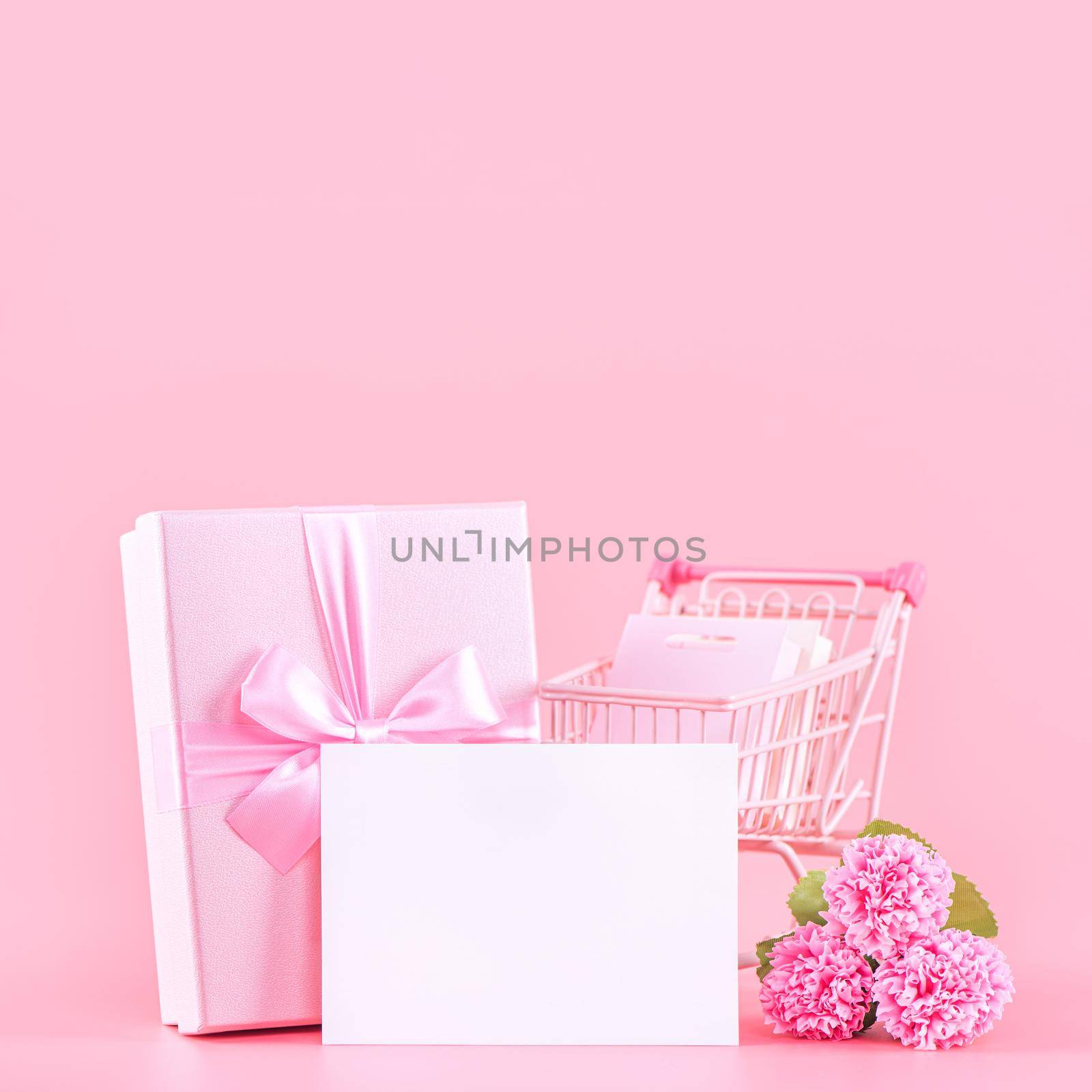 Mother's Day holiday gift design concept, pink carnation flower bouquet with wrapped gift box isolated on pink background, copy space.