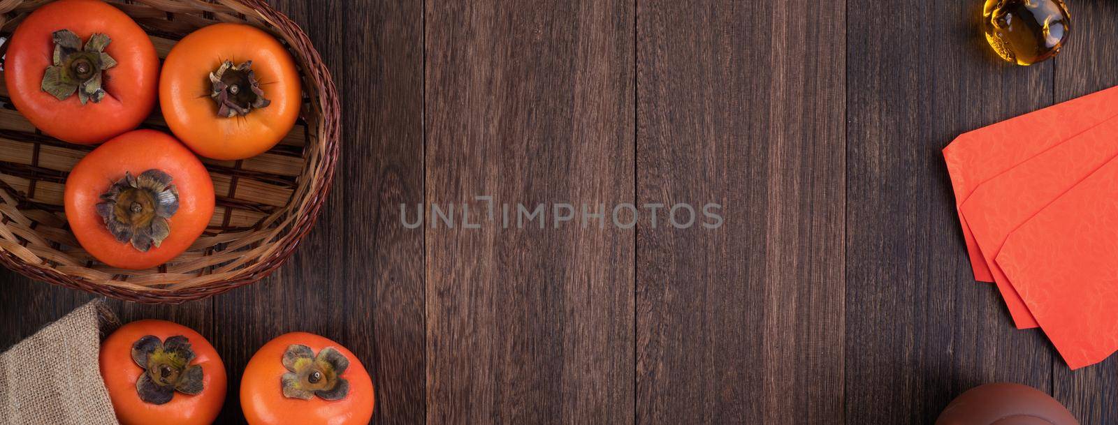 Top view of fresh sweet persimmons kaki with leaves on wooden table background for Chinese lunar new year fruit design concept, the word means blessing is coming.