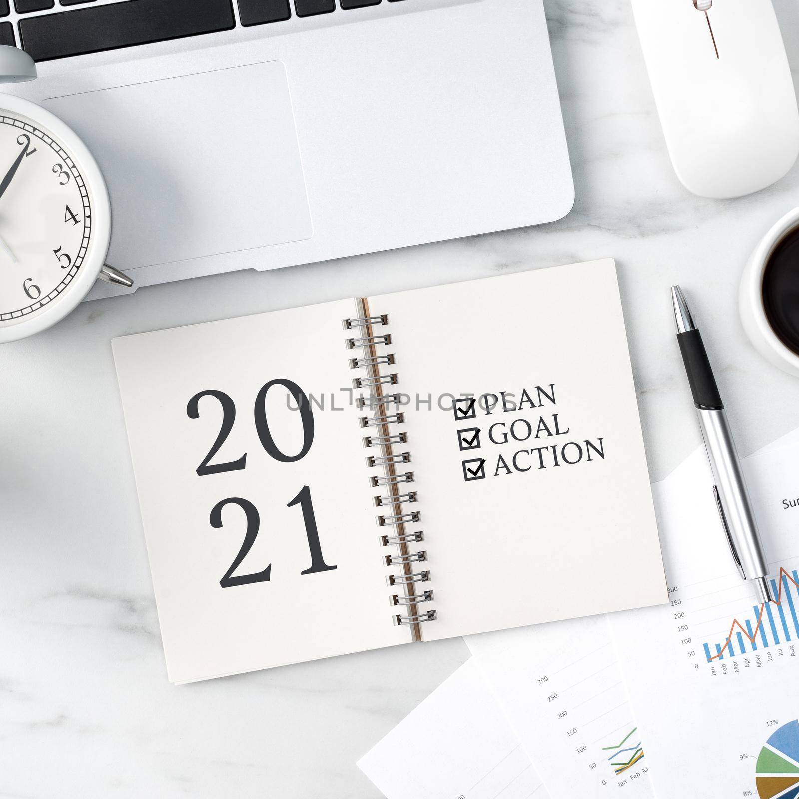 Top view of office table desk 2021 Goal work concept with keyboard, notebook, pencil, eyeglasses and coffee on bright marble white background.