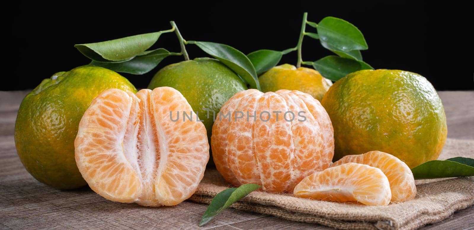 Fresh green tangerine mandarin orange with fresh leaves on dark wooden table background harvest concept.