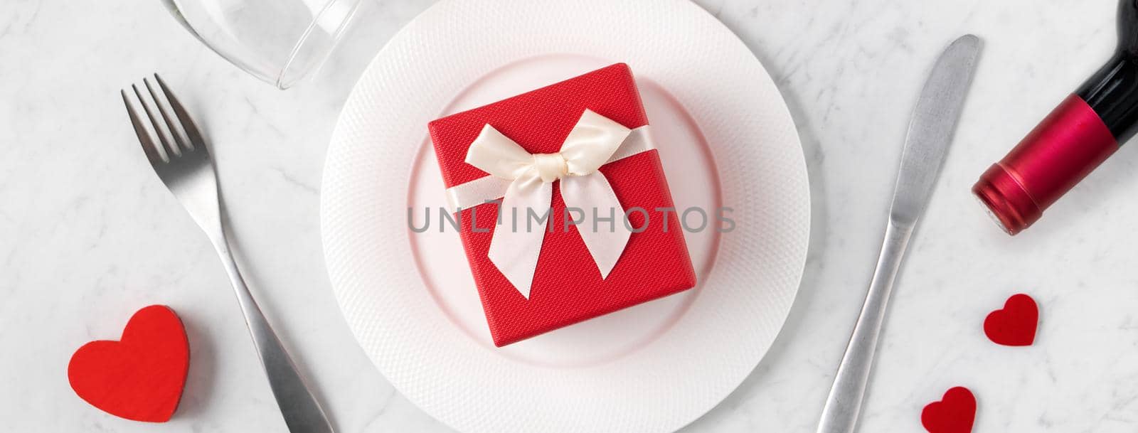 Empty white plate with tableware, ribbon, gift and roses for Valentine's Day special holiday dating meal concept.