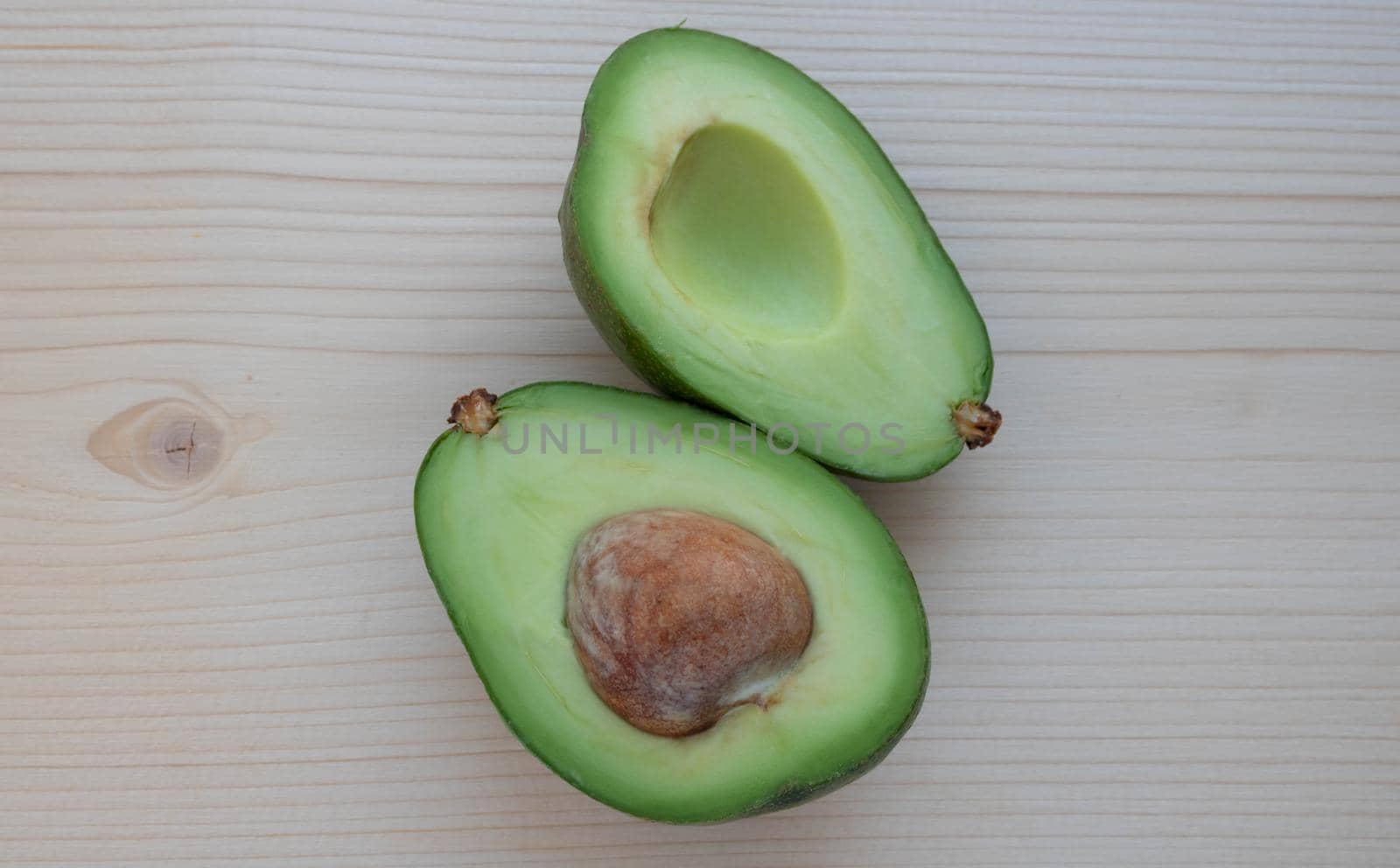Slices of ripe avocado lie on a light cutting board.